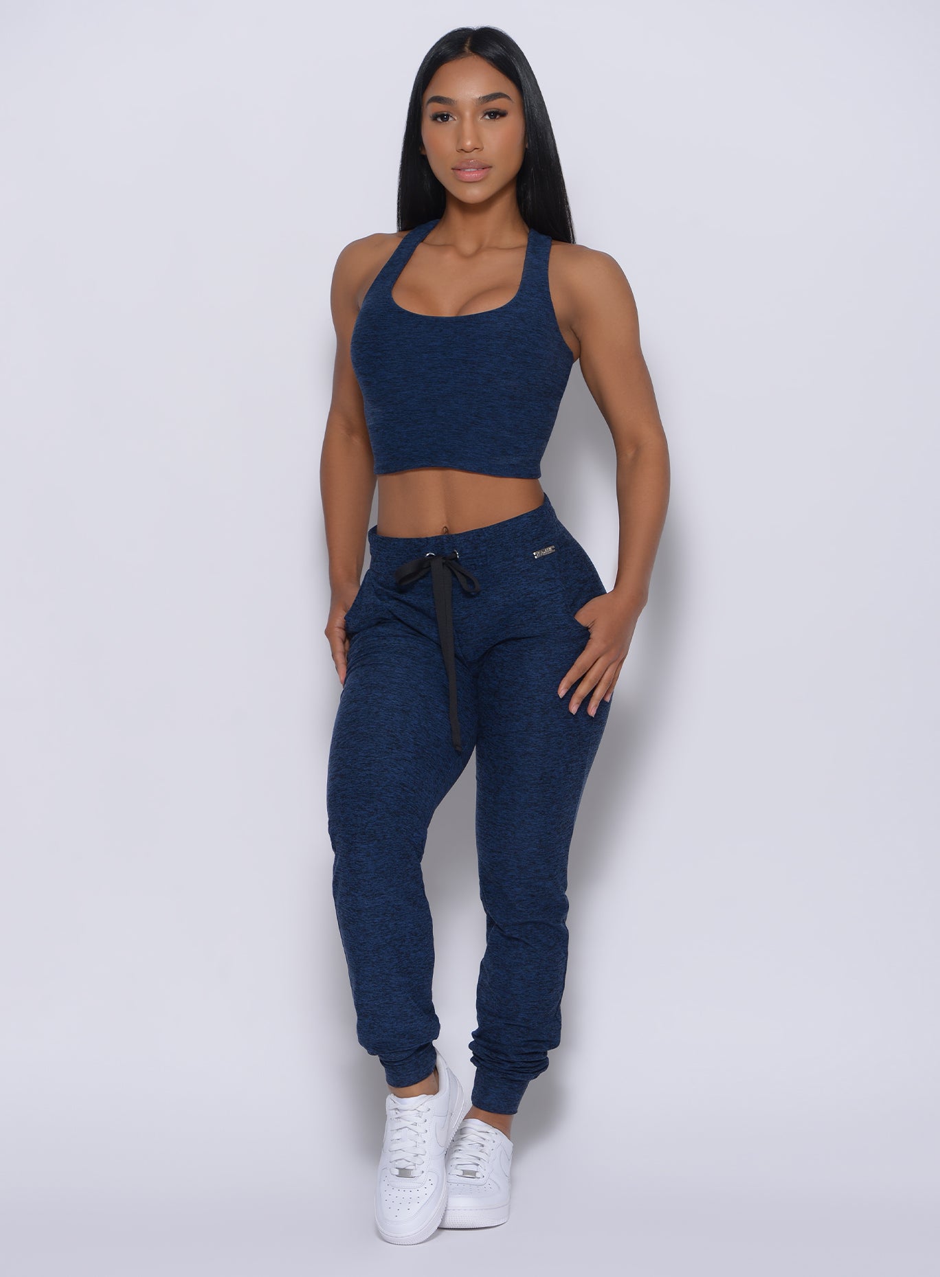 Front profile view of a model in our signature joggers in sapphire blue color and a matching bra 
