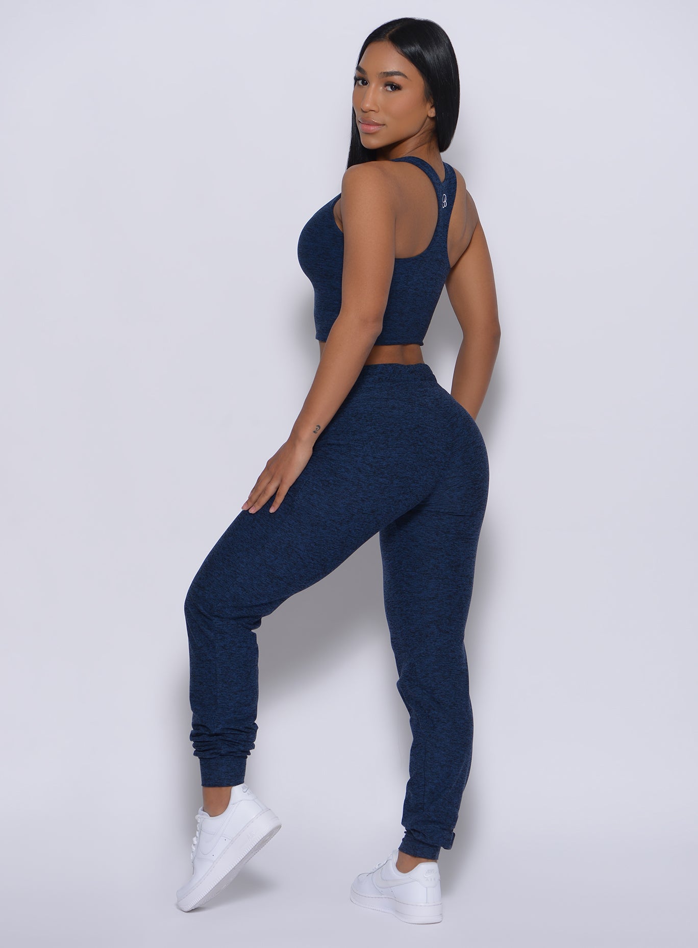 Left side profile view of a model in our signature joggers in sapphire blue color and a matching bra