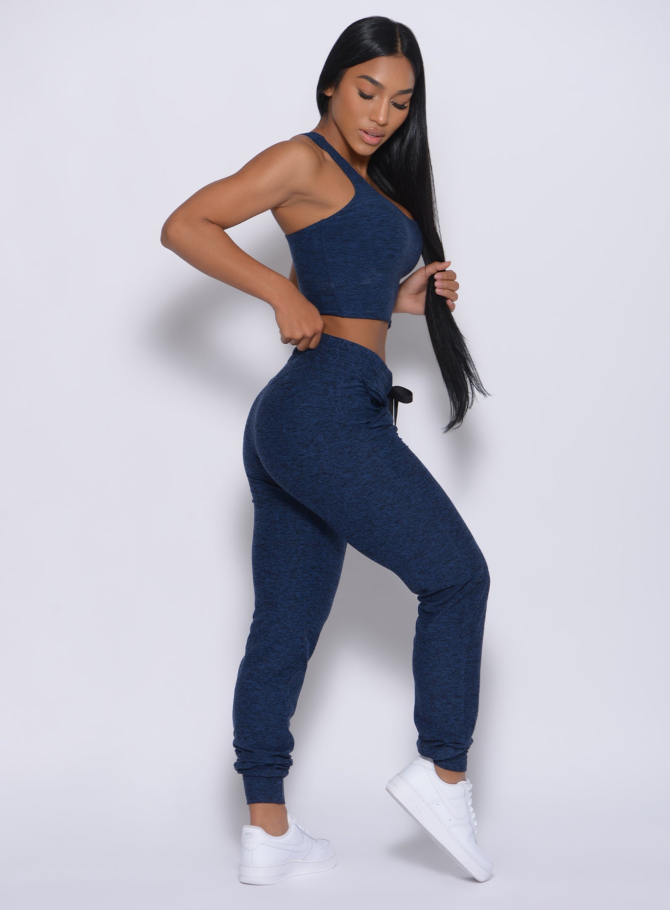 Right side profile view of a model in our signature joggers in sapphire blue color and a matching bra