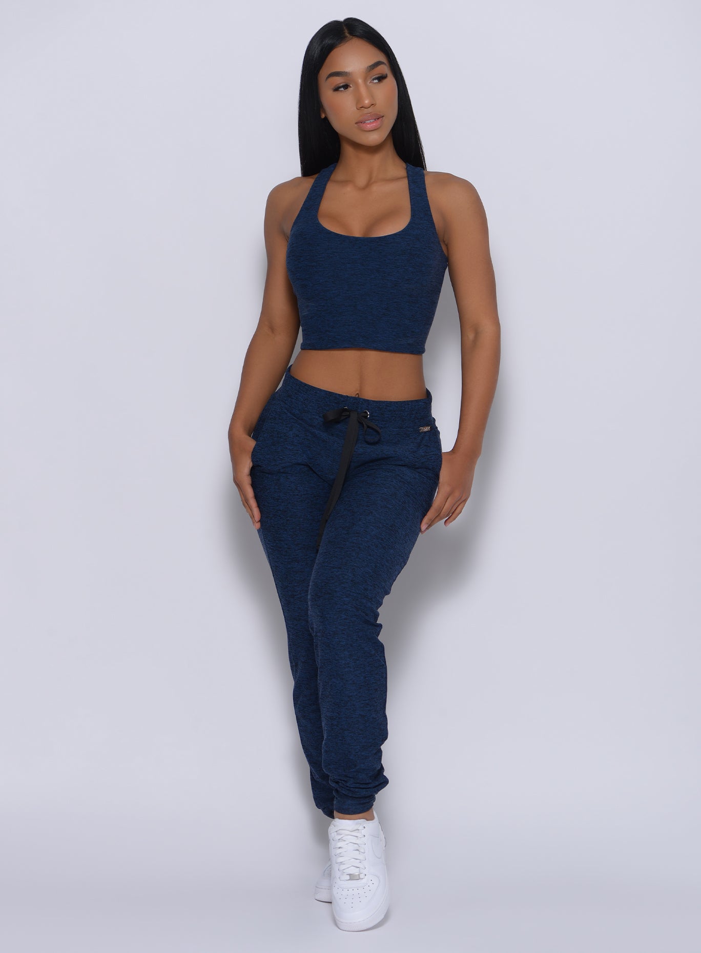 Front profile view of a model wearing our signature joggers in sapphire blue color and a matching bra