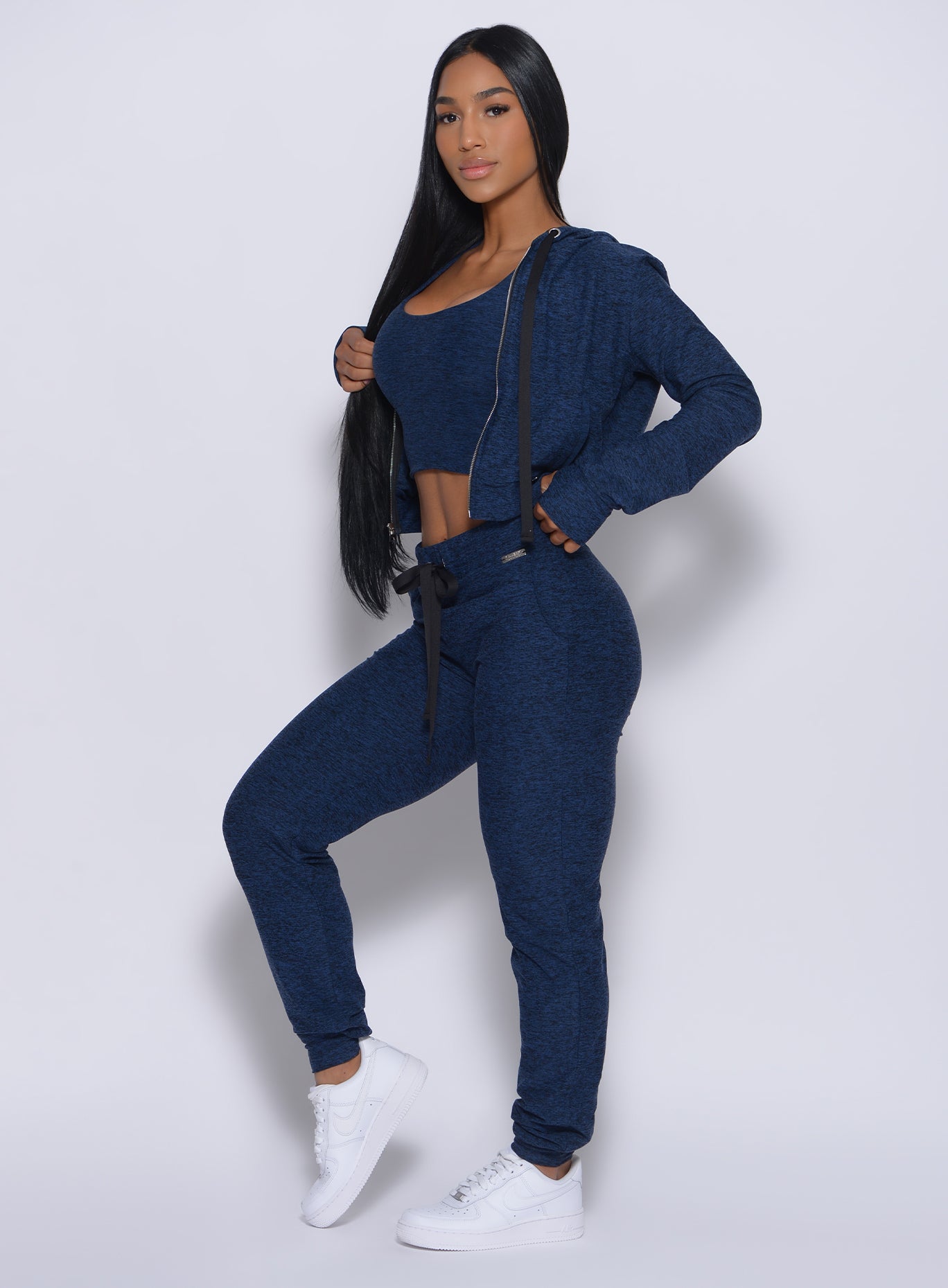 Left side profile view of a model angled left wearing our signature joggers in sapphire blue color and a matching jacket