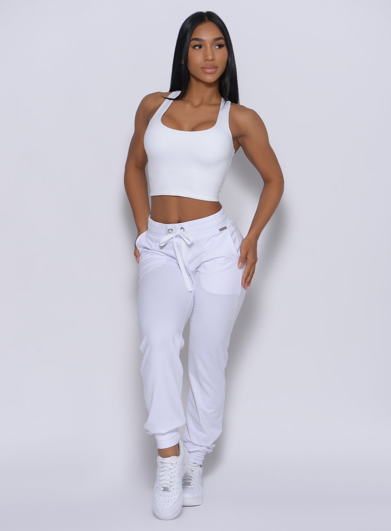 Front  profile view of the model wearing our white elevated tank bra and a matching joggers