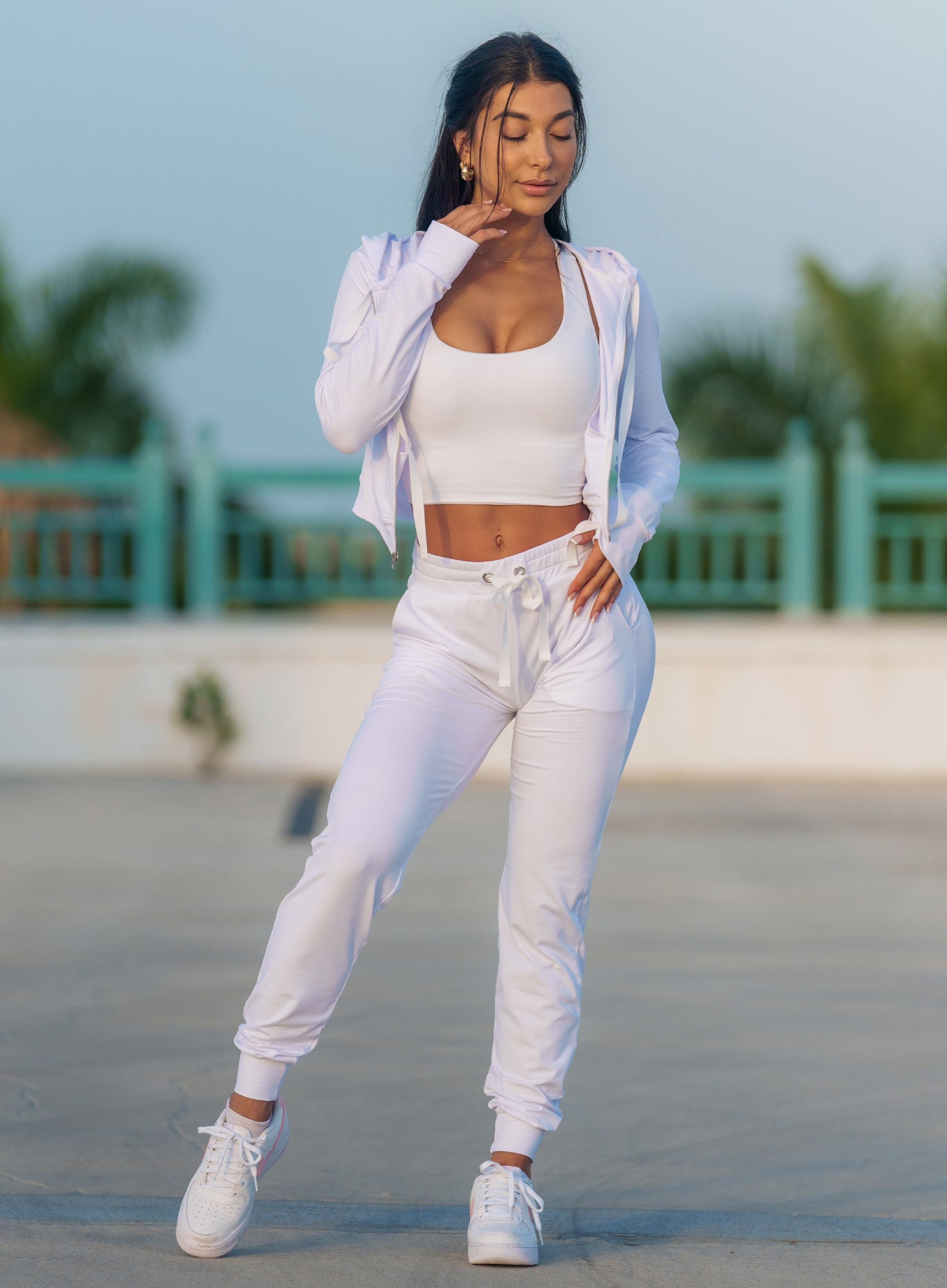 Front profile view of a model in our white signature joggers and a matching Sports bra