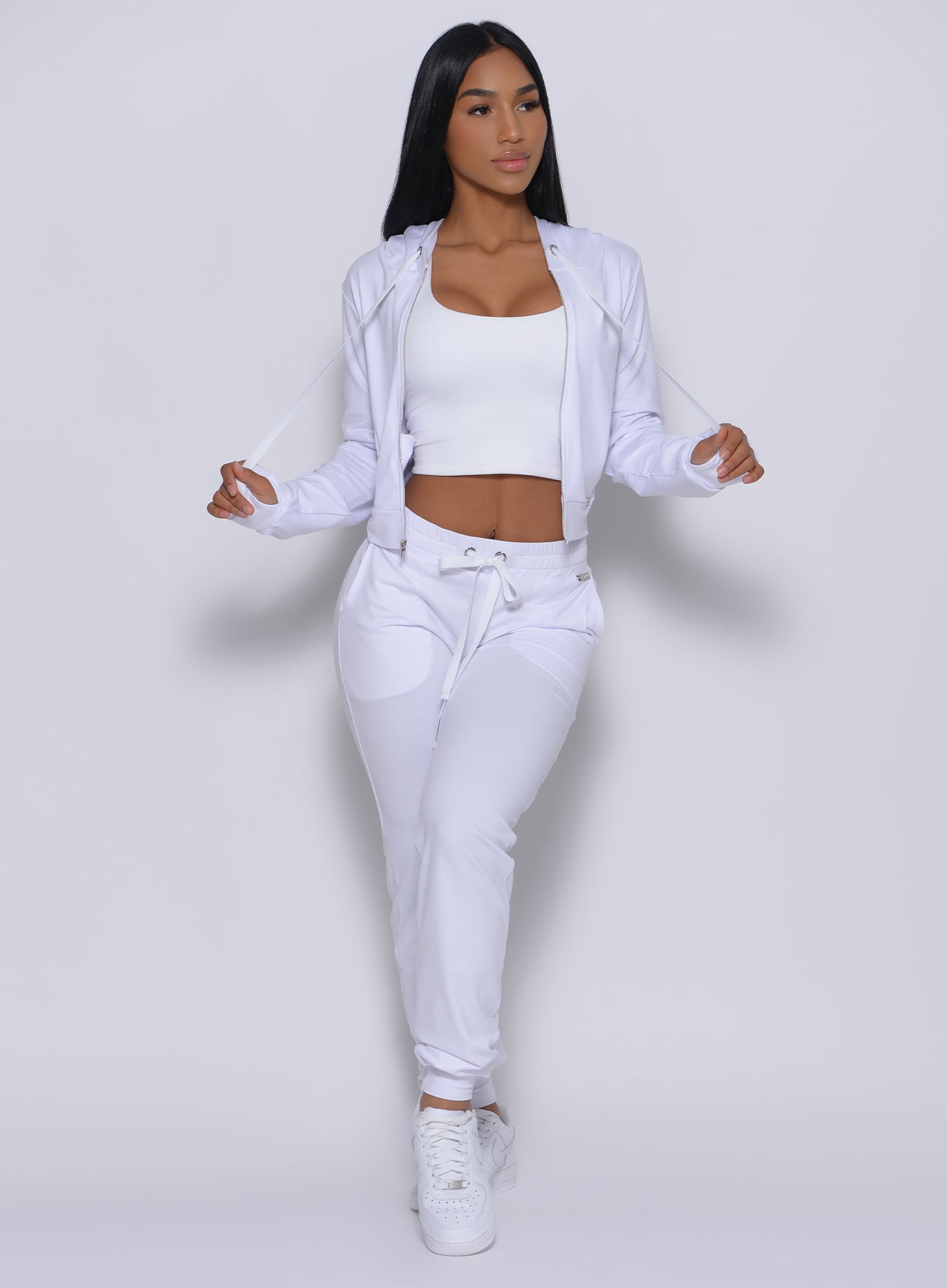 Front profile view of a model facing to her left wearing our white signature joggers and a matching bra
