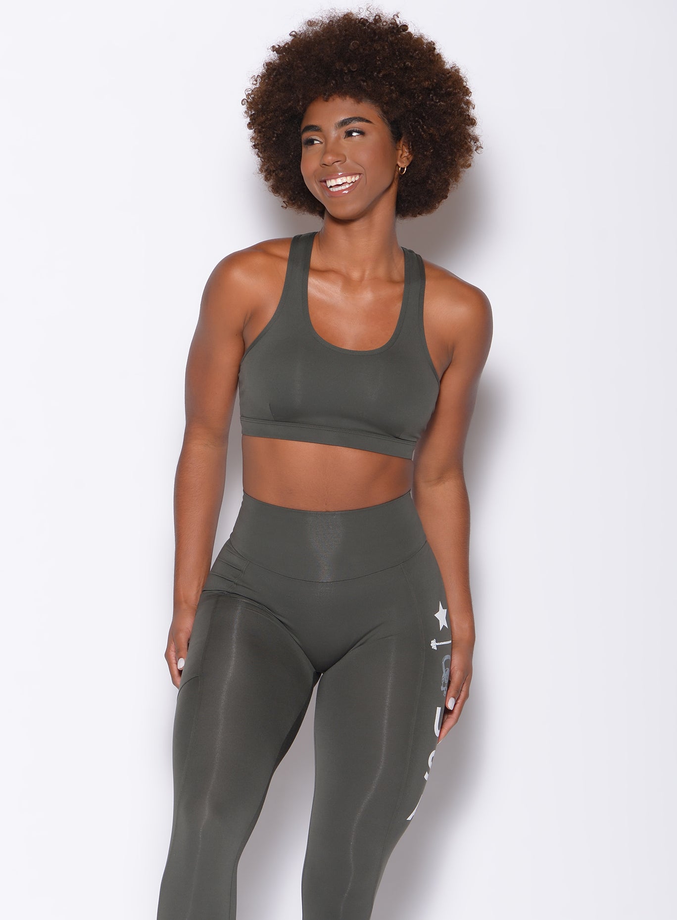 front view of model in a solid hunter green gym set with side print down one leg