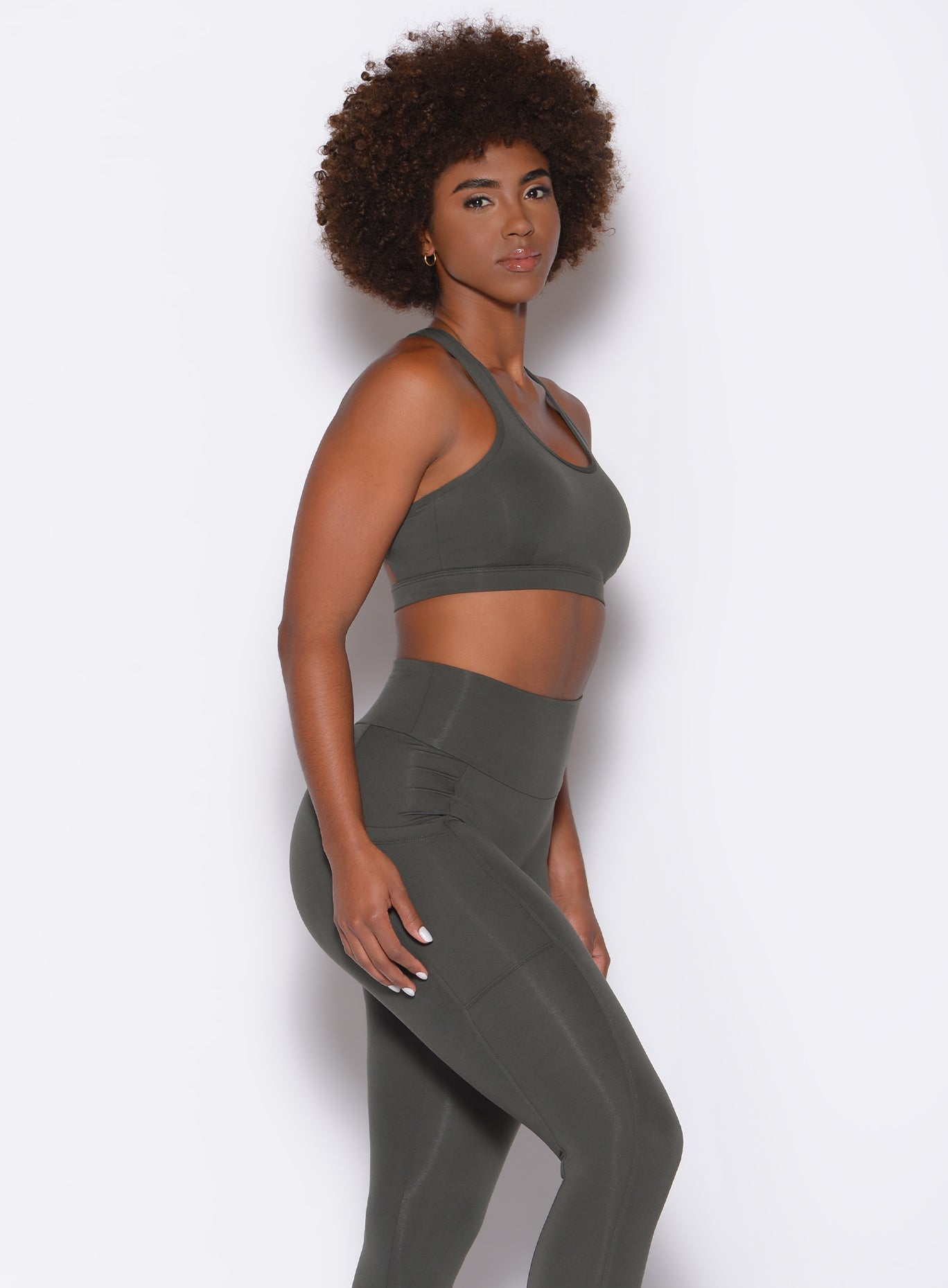side view of model in a two piece gym set in hunter green