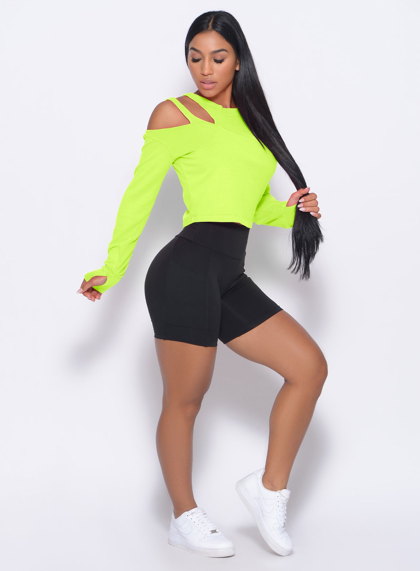 Right side view of the model in our black pocket biker shorts and a neon yellow pullover