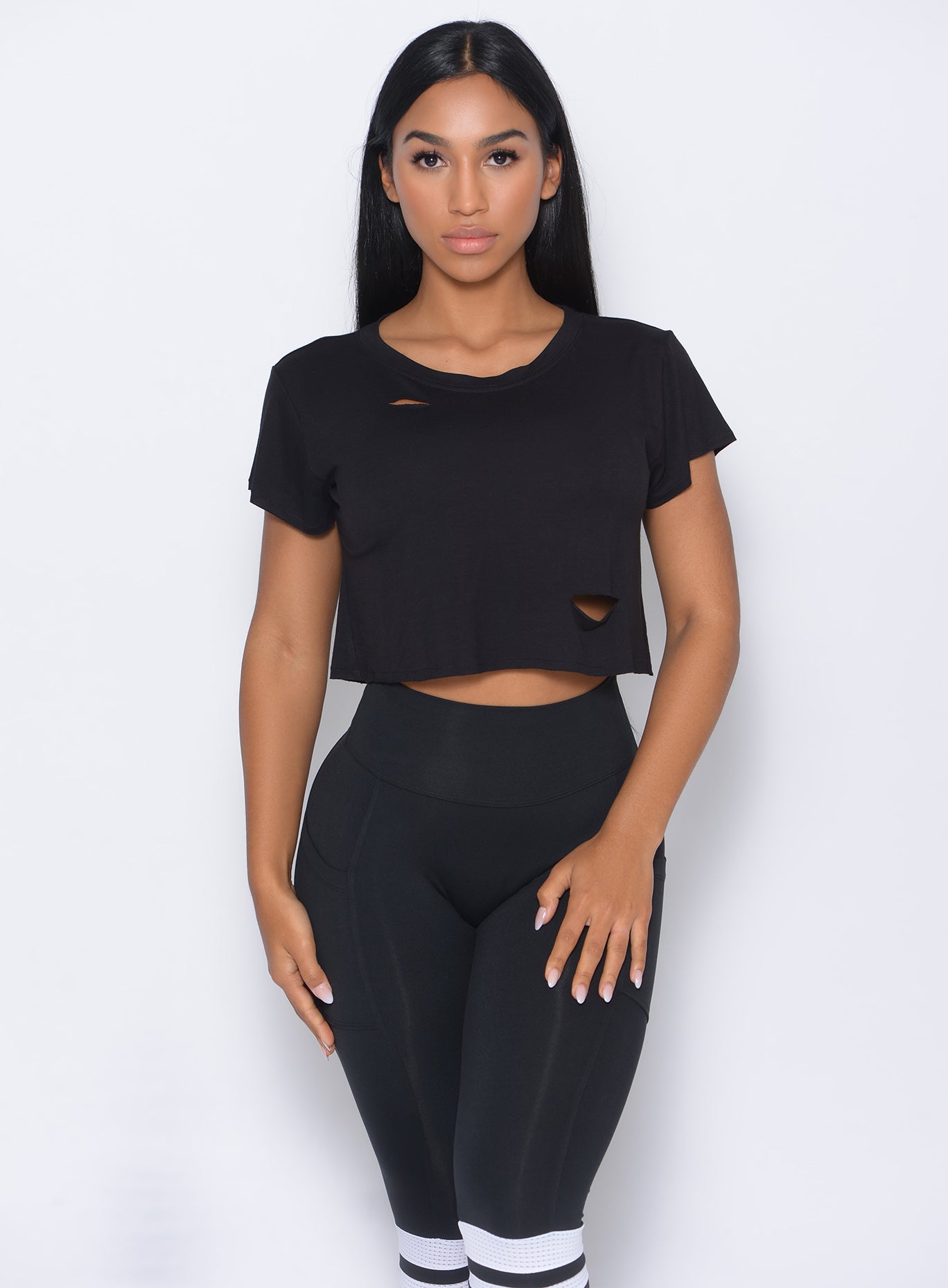 Front profile view of the model in our black shredded tee and a matching leggings