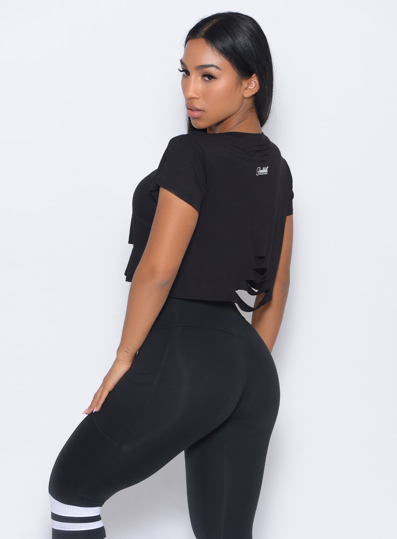 Left side view of the model in our black shredded tee and a matching leggings