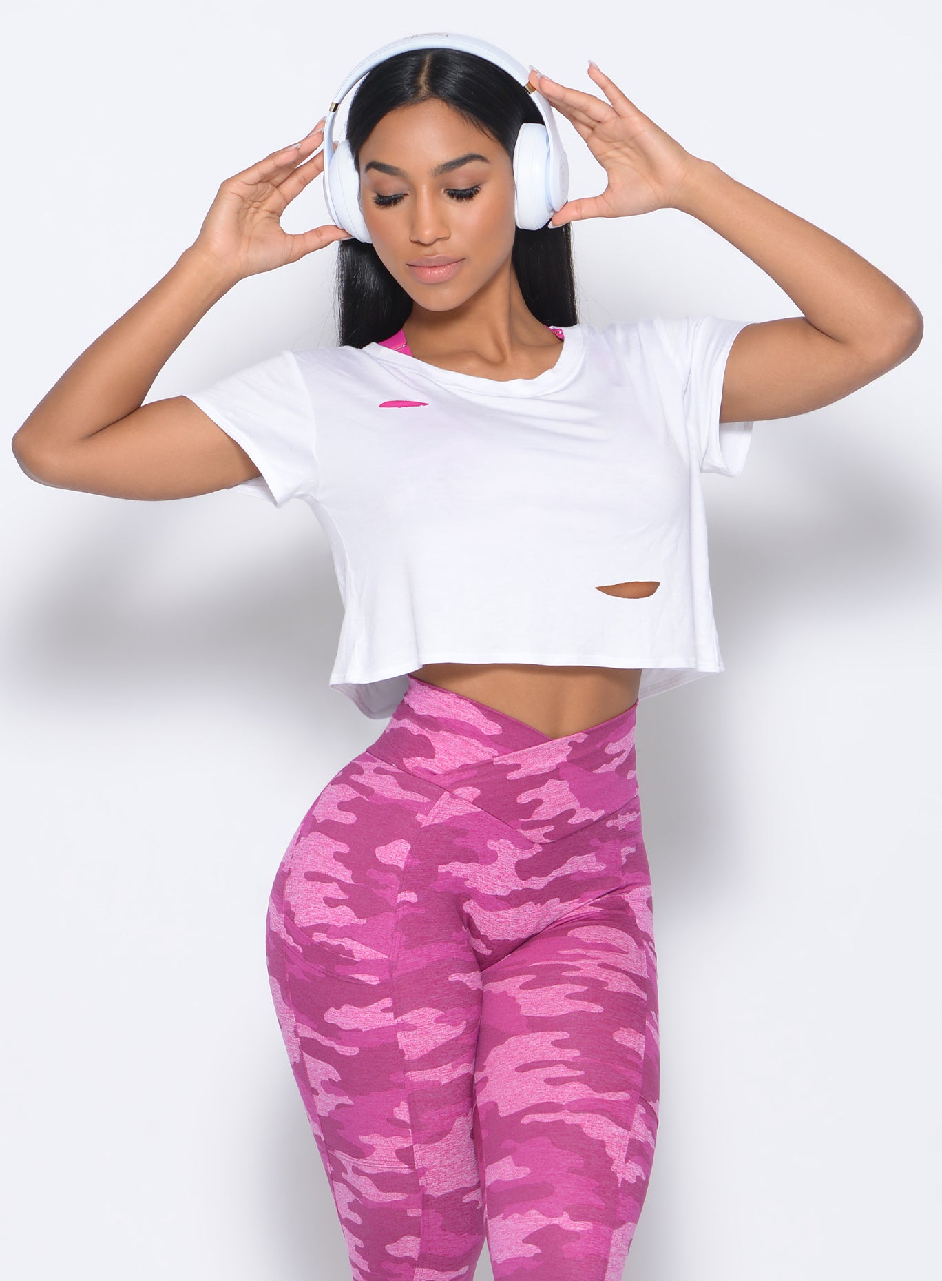 Front profile  view of the model in our white shredded tee and a pink camo leggings