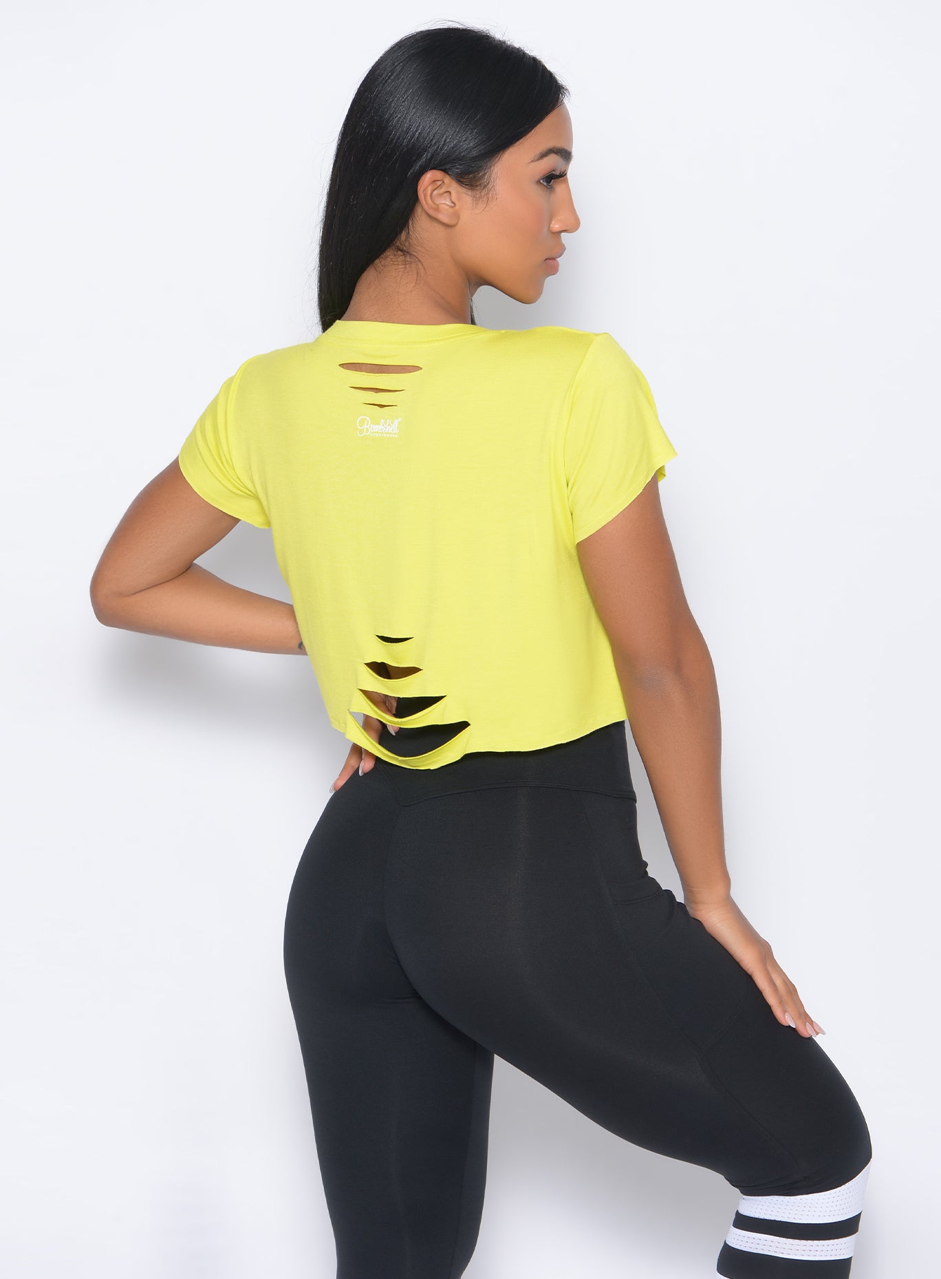 Back view of the model in our shredded tee in neon yellow and a black leggings