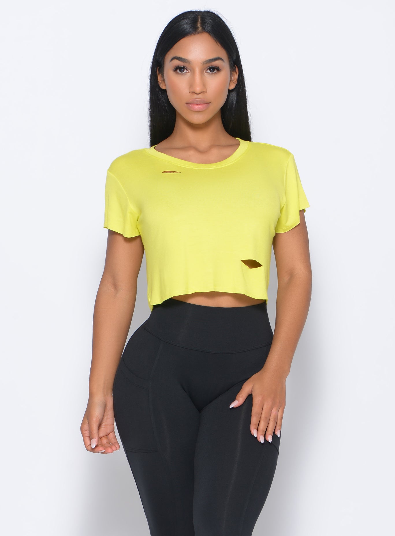 Front profile  view of the model wearing our shredded tee in neon yellow and a black leggings