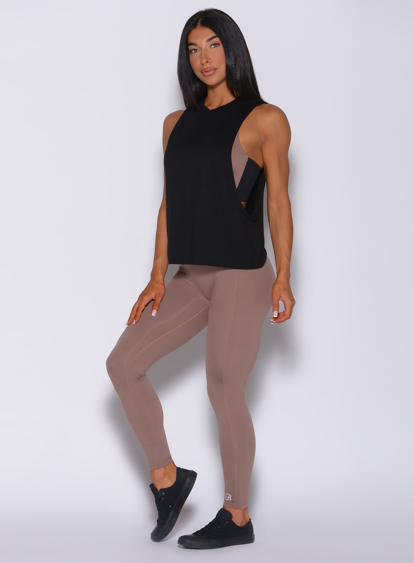 Front profile view of a model in our snatched waist leggings in cocoa color and a black tank top
