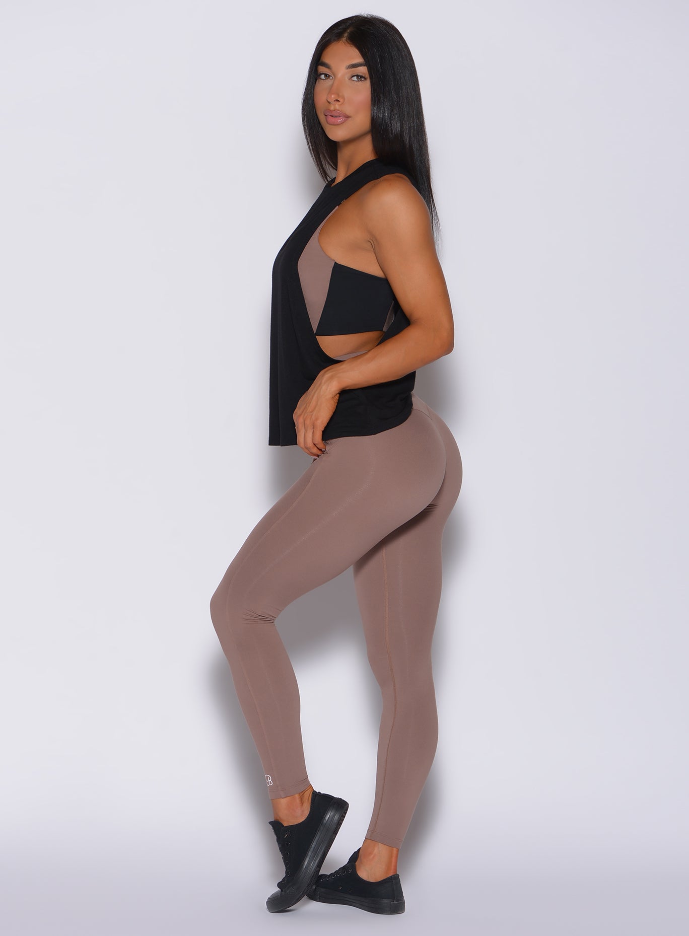Left side profile view of a model in our snatched waist leggings in cocoa color and a black tank top 