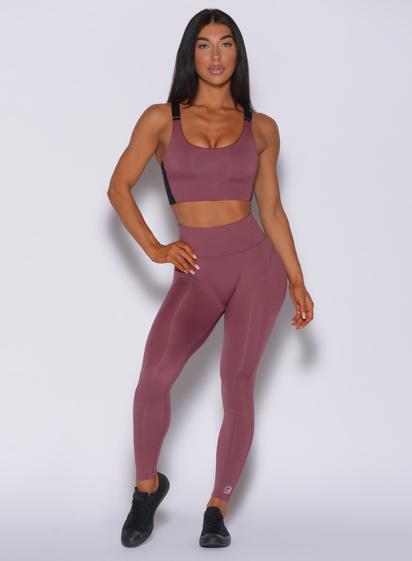 Model facing forward wearing our snatched waist leggings in merlot color and a matching bra