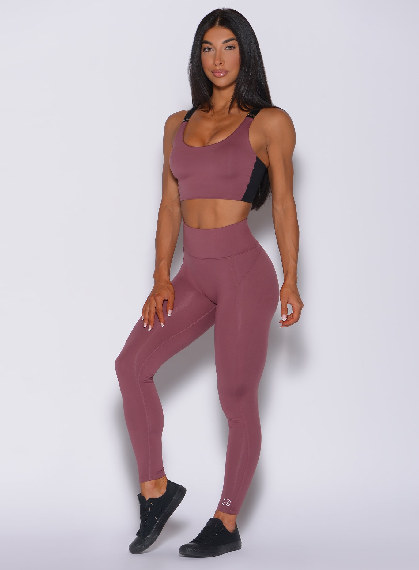 Picture of a model facing forward wearing our snatched waist leggings in merlot color and a matching bra