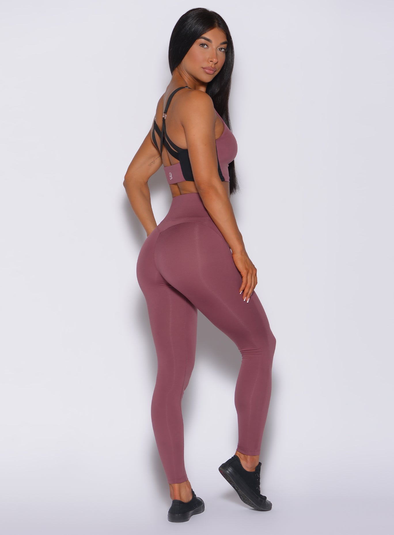 Right side profile view of a model in our snatched waist leggings in merlot color and a matching bra