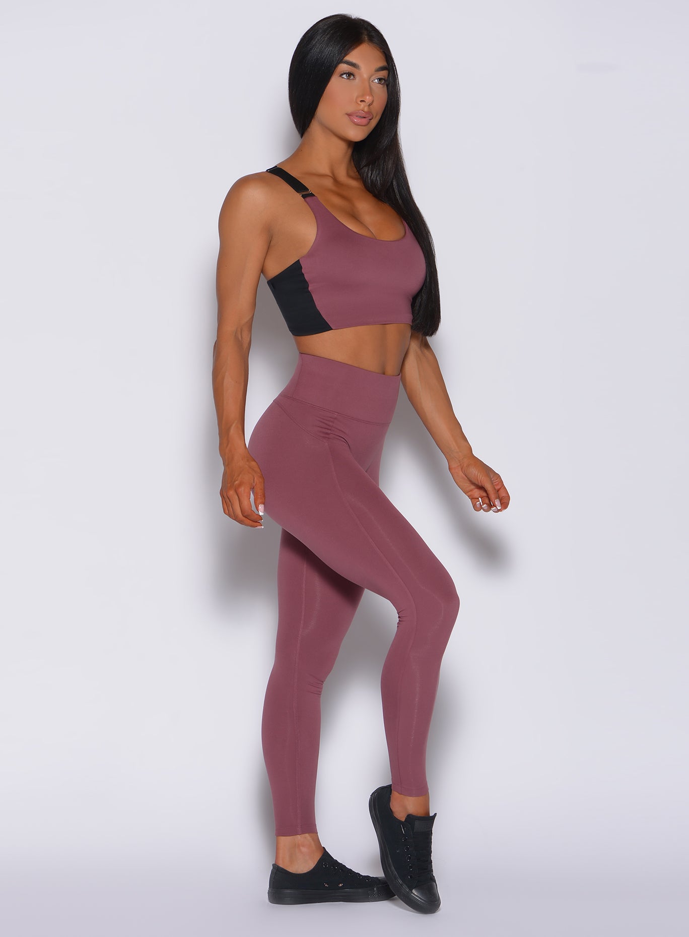 Right side profile view of a model wearing our snatched waist leggings in merlot color and a matching bra