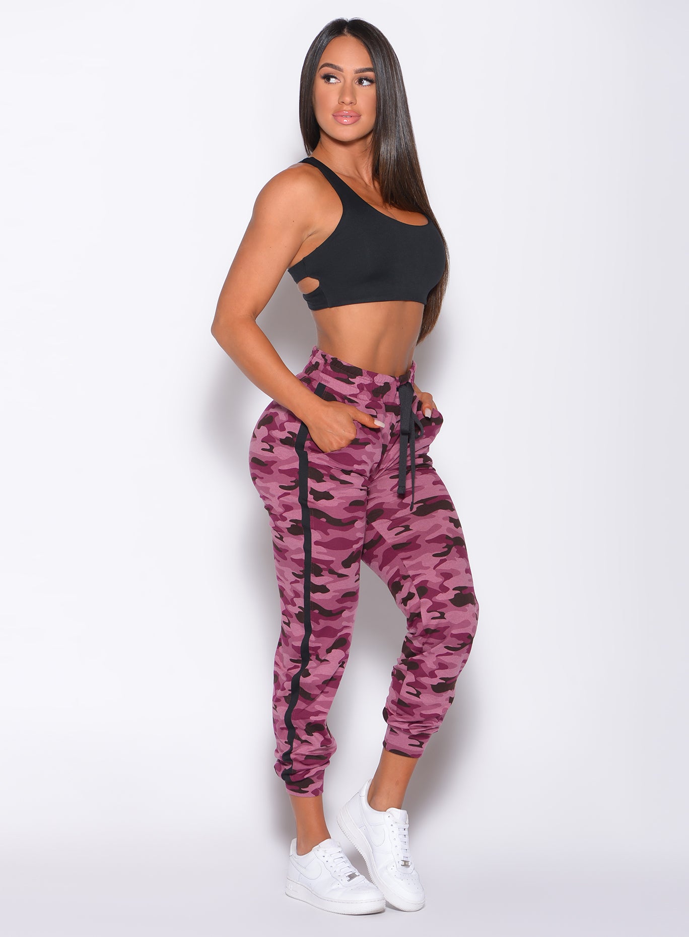 Right side  profile view of a model facing to her right wearing our dream joggers in Purple Power Camo color and a black bra 