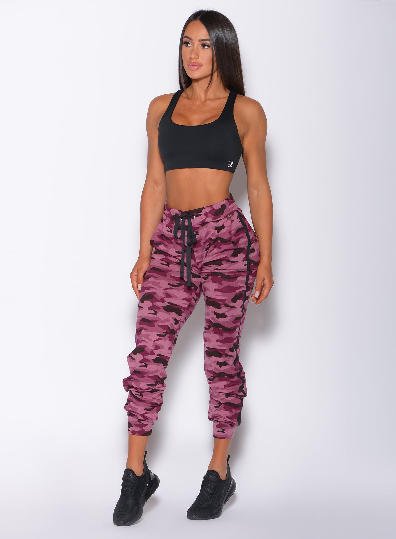 Front profile view of a model wearing our dream joggers in Purple Power Camo color and a matching black bombshell sports bra 