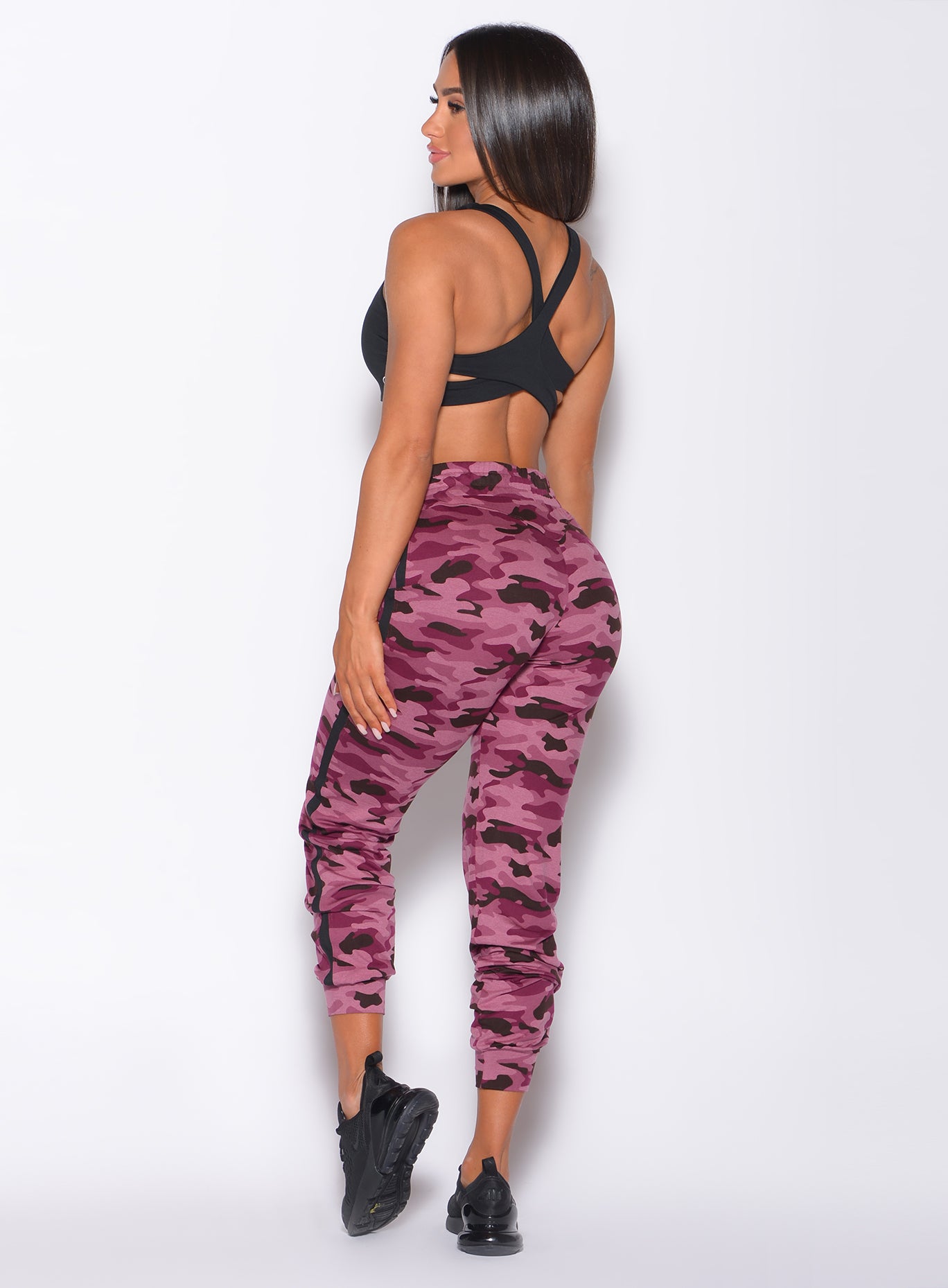 Back  profile view of a model in our dream joggers in Purple Power Camo color and a black bra 