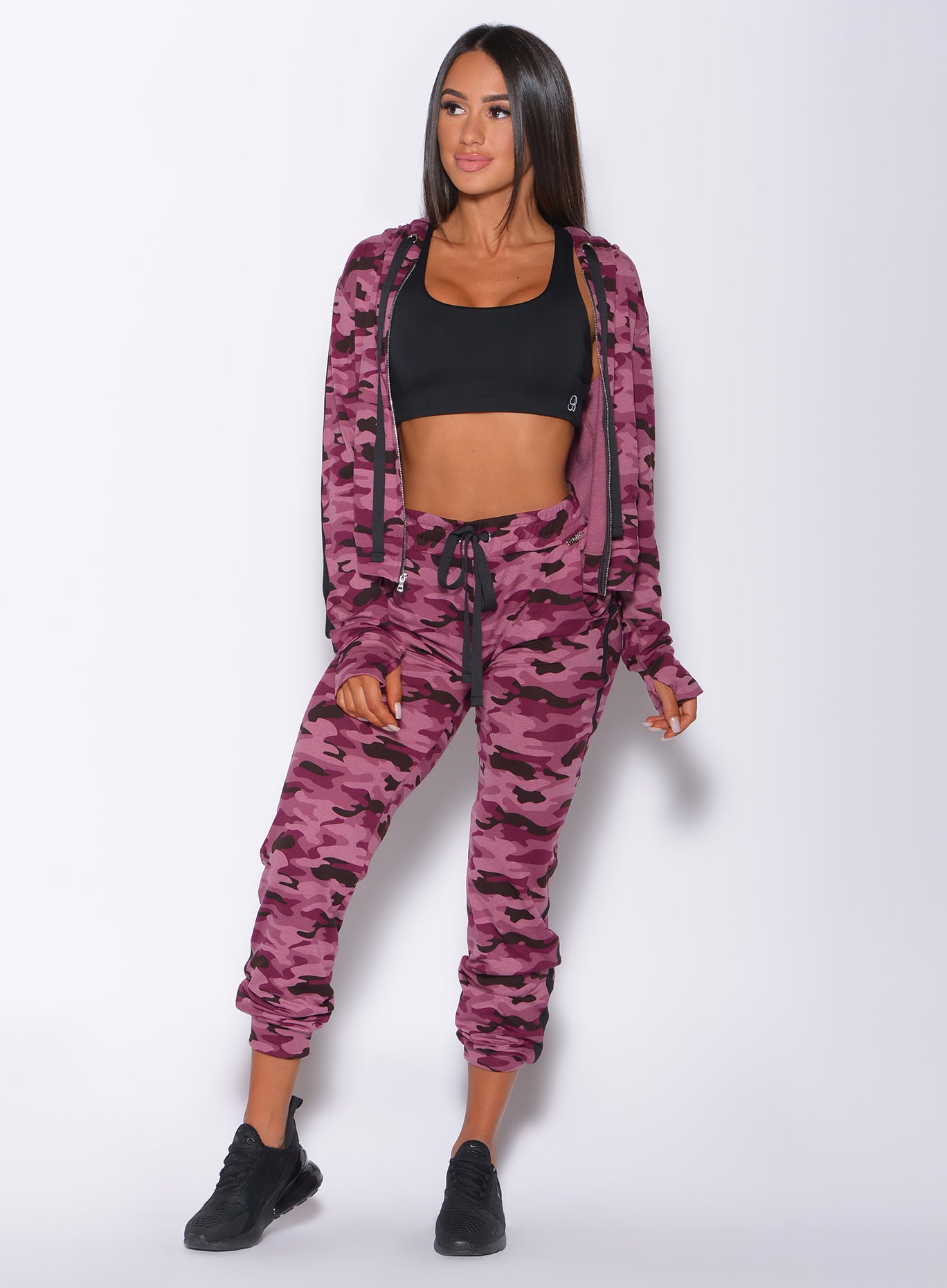 Front profile view of a model looking to her right wearing our dream jacket in Purple Power Camo color and a matching joggers