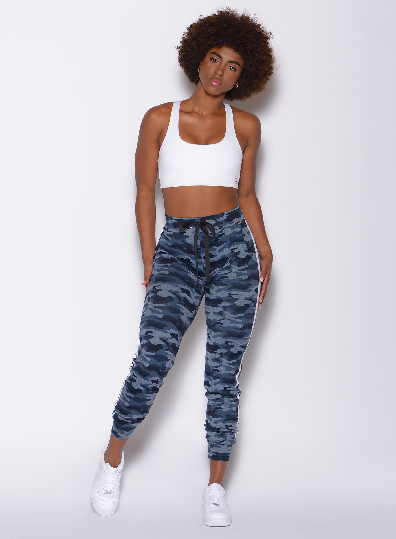 Front profile view of a model in our dream joggers in Blue Blast Camo color and a white bra 