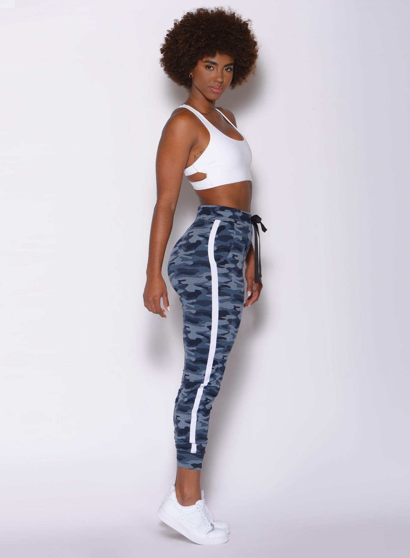 Right side profile view of a model in our dream joggers in Blue Blast Camo color and a white sports bra 