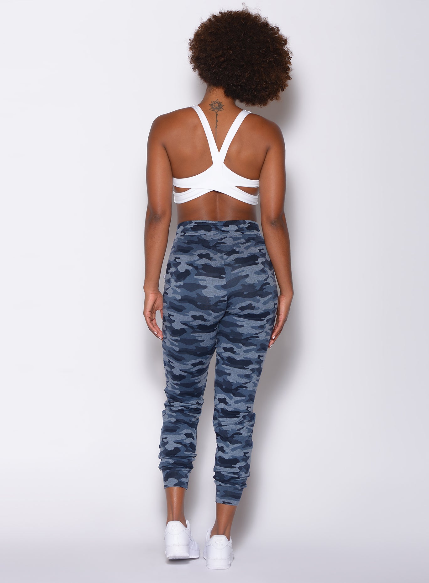 Back side profile view of a model in our dream joggers in Blue Blast Camo color and a white sports bra 