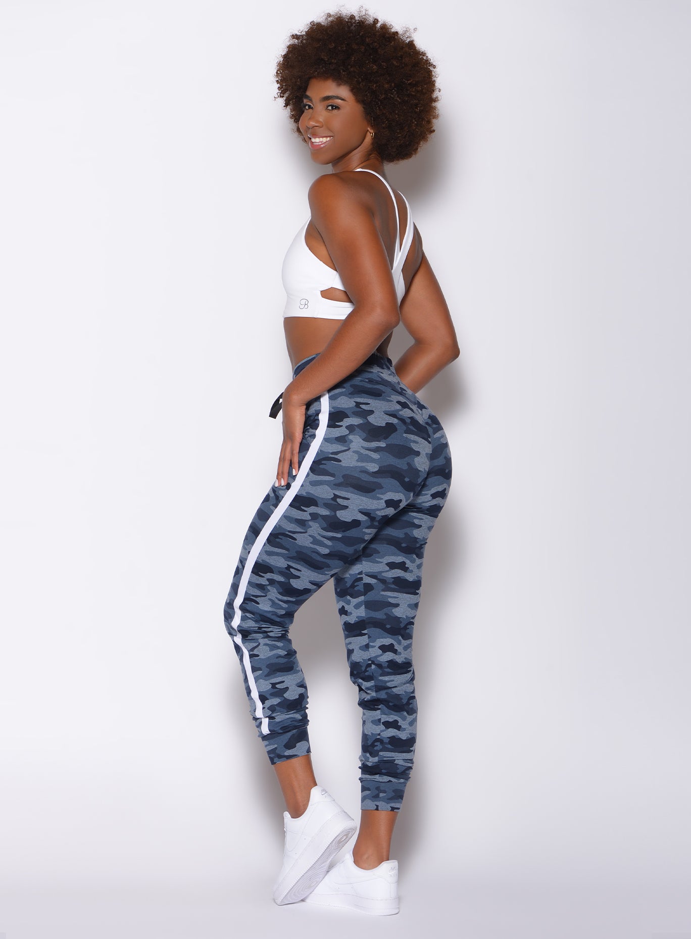 Left side profile view of a model in our dream joggers in Blue Blast Camo color and a white sports bra 