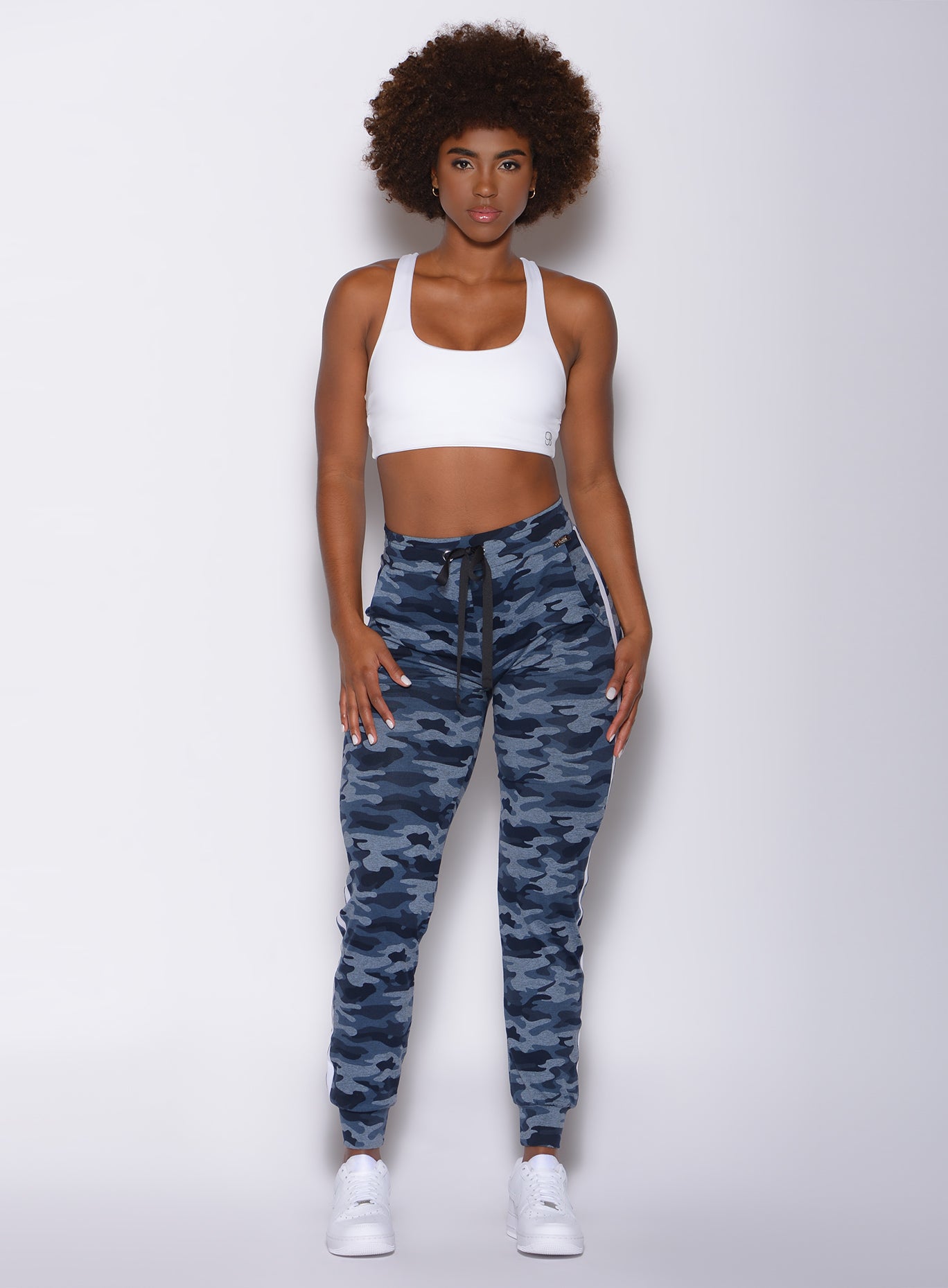 Front profile view of a model in our dream joggers in Blue Blast Camo color and a white bra 
