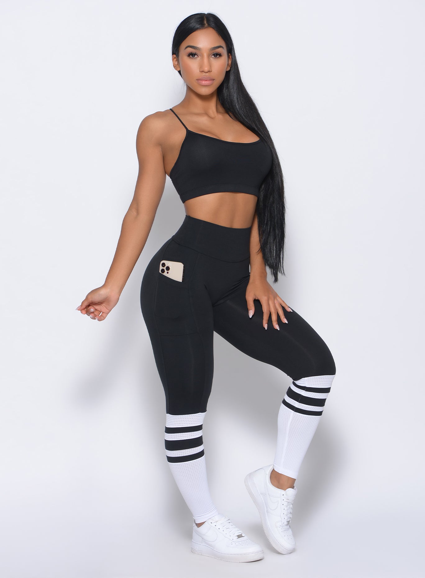 Front profile view of the model with her left hand on thigh wearing our sock leggings in black white color 