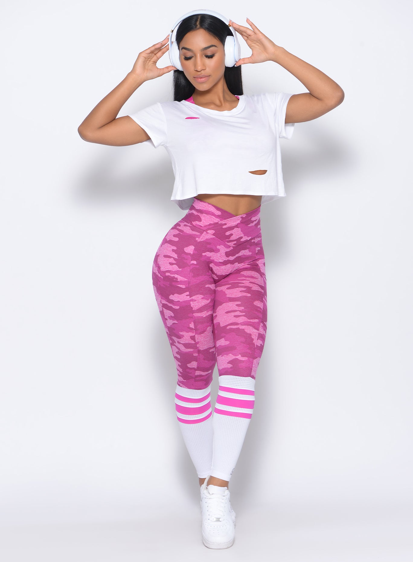 Model facing forward wearing our white shredded tee and a pink camo sock leggings
