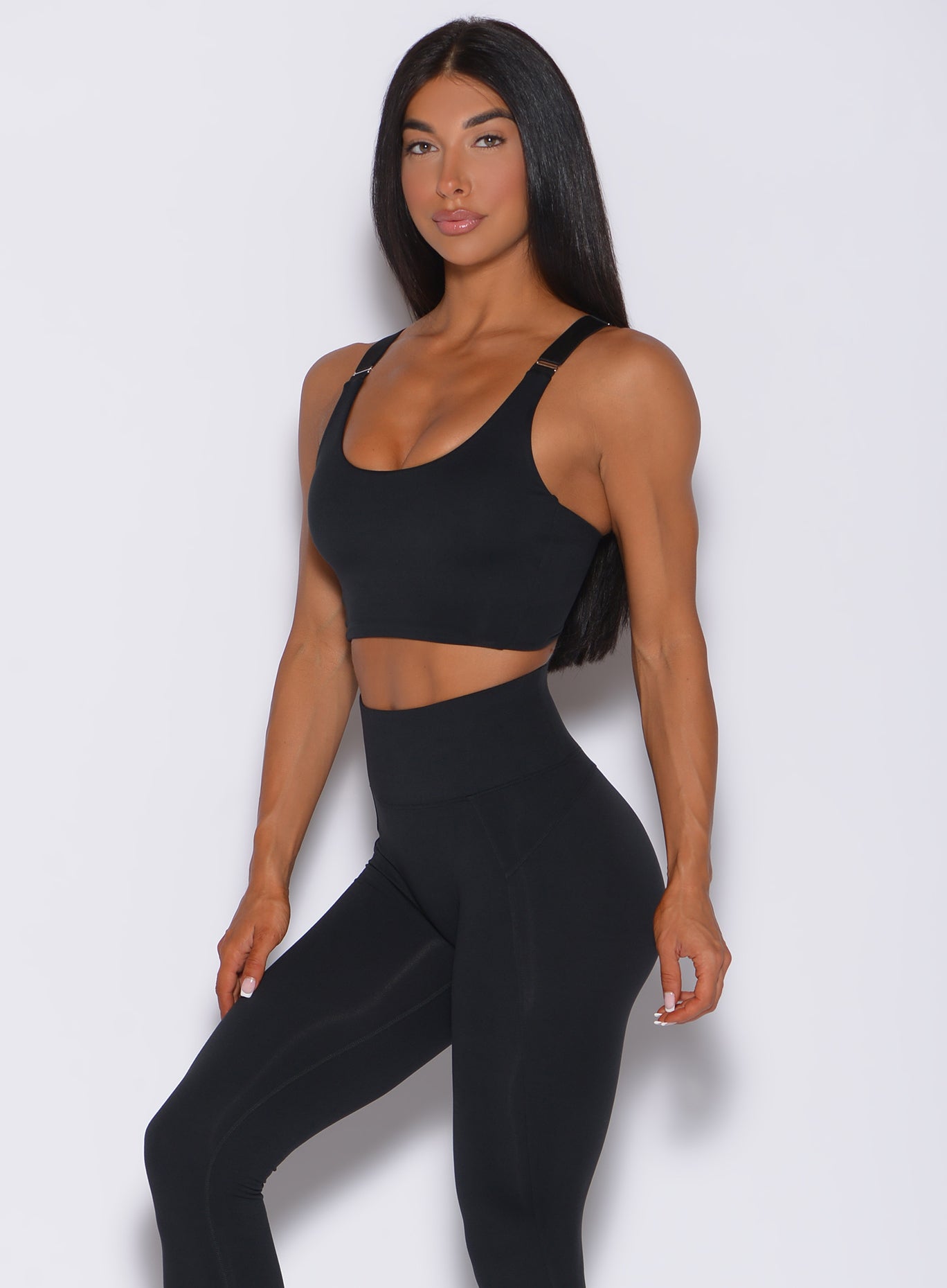 Front profile view of a model wearing  our banded sports bra in black and a matching high waist leggings