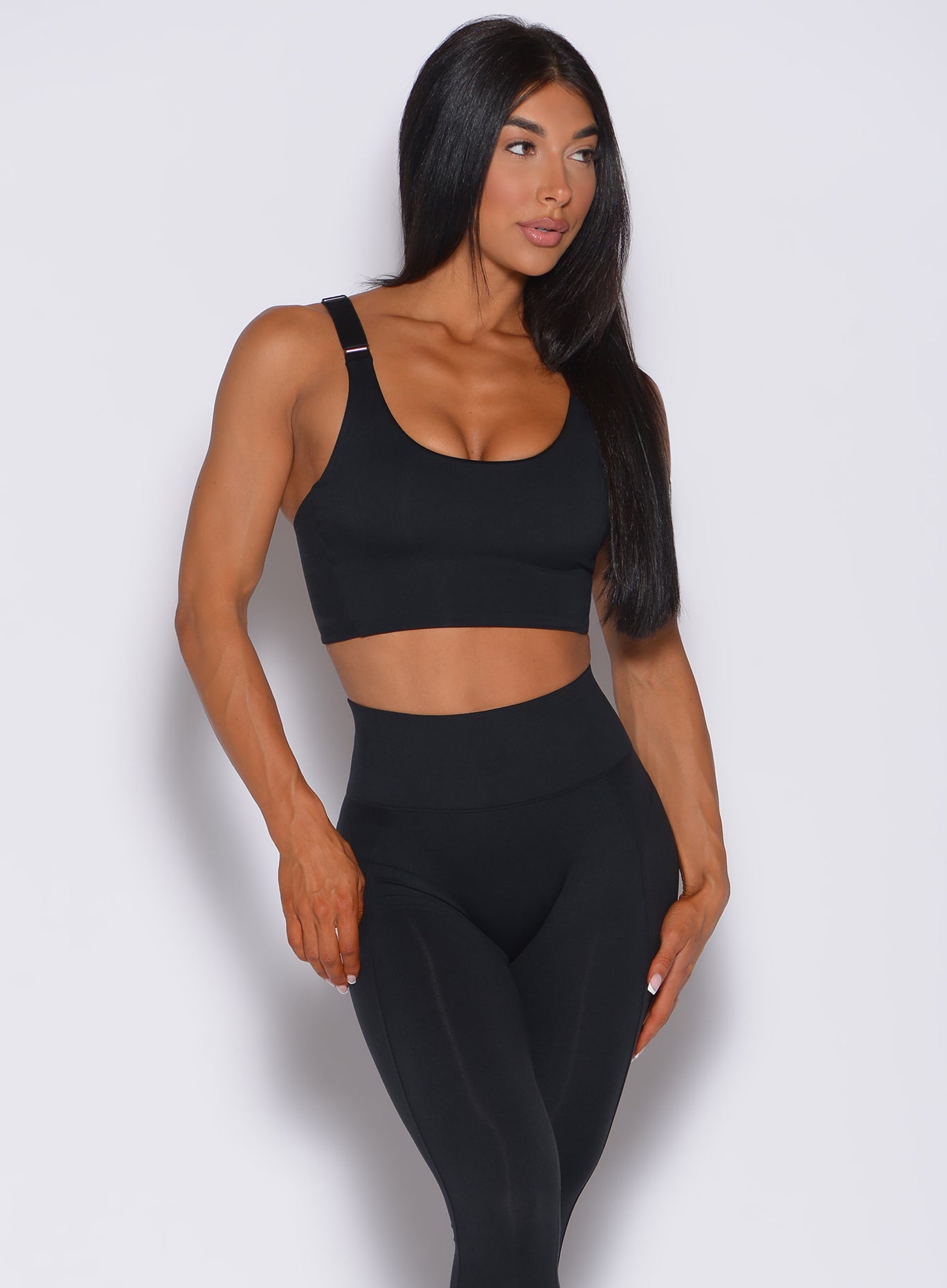 Front profile view of a model facing to her left wearing  our banded sports bra in black and a matching leggings