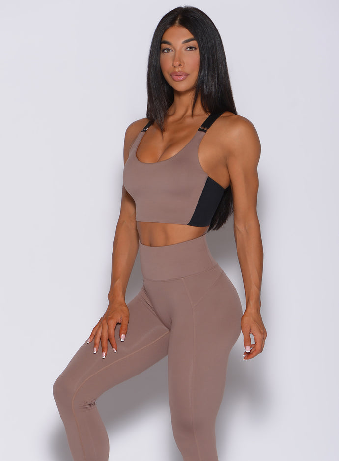 Left side  profile view of a model facing to her left wearing  our banded sports bra in cocoa color and a matching leggings