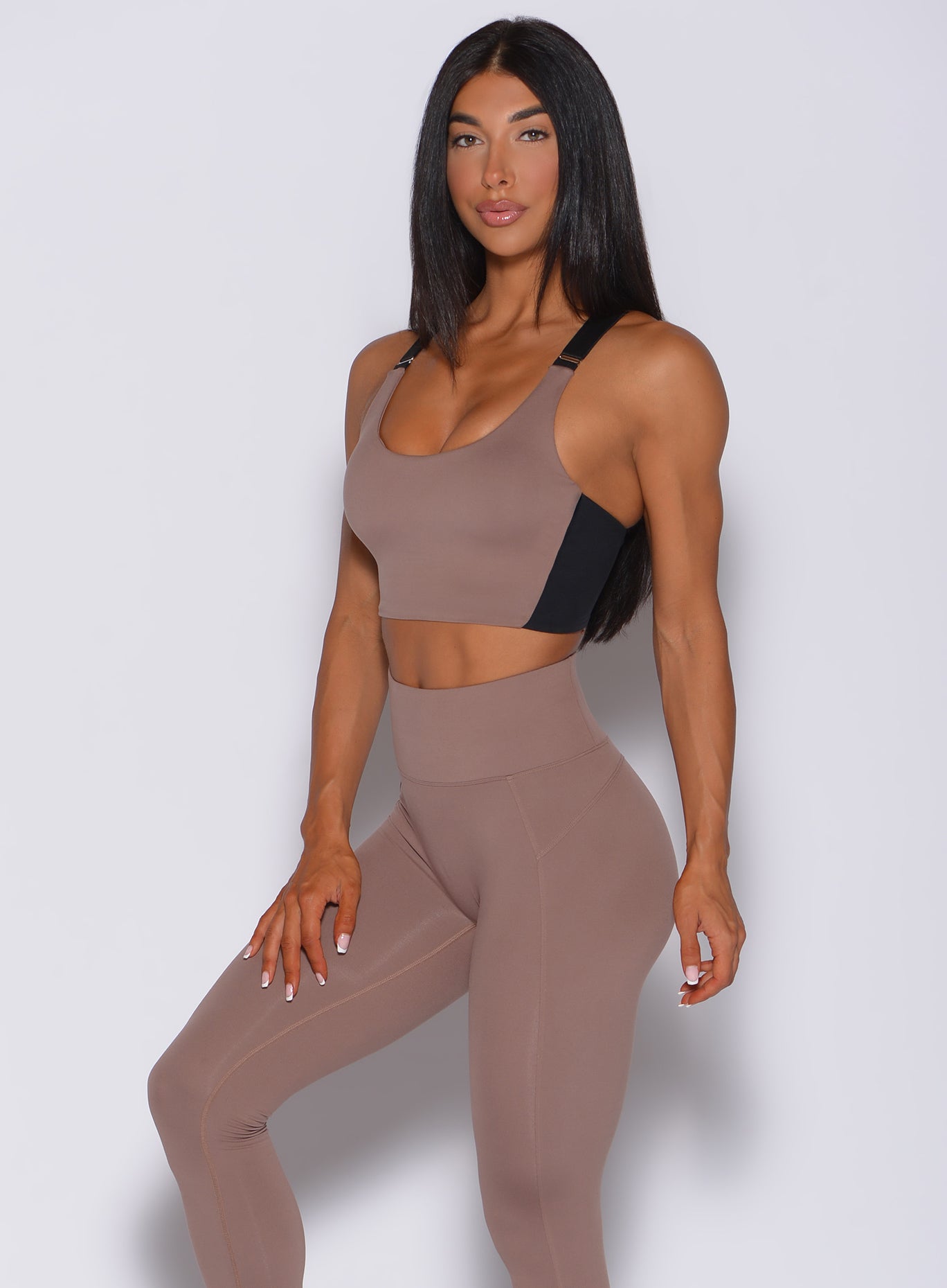 Left side  profile view of a model facing to her left wearing  our banded sports bra in cocoa color and a matching leggings