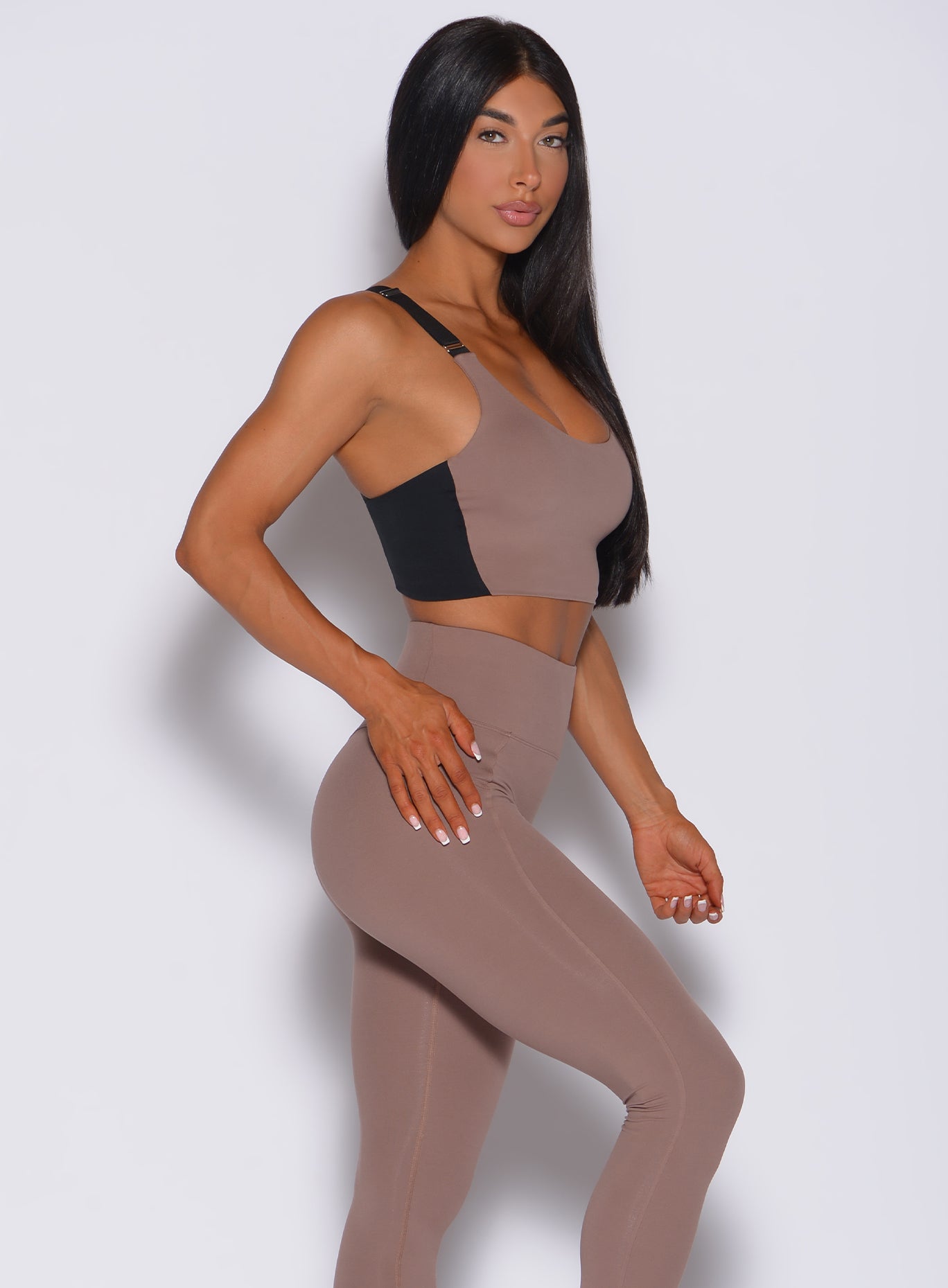 Right side  profile view of a model facing to her right wearing our banded sports bra in cocoa color and a matching leggings