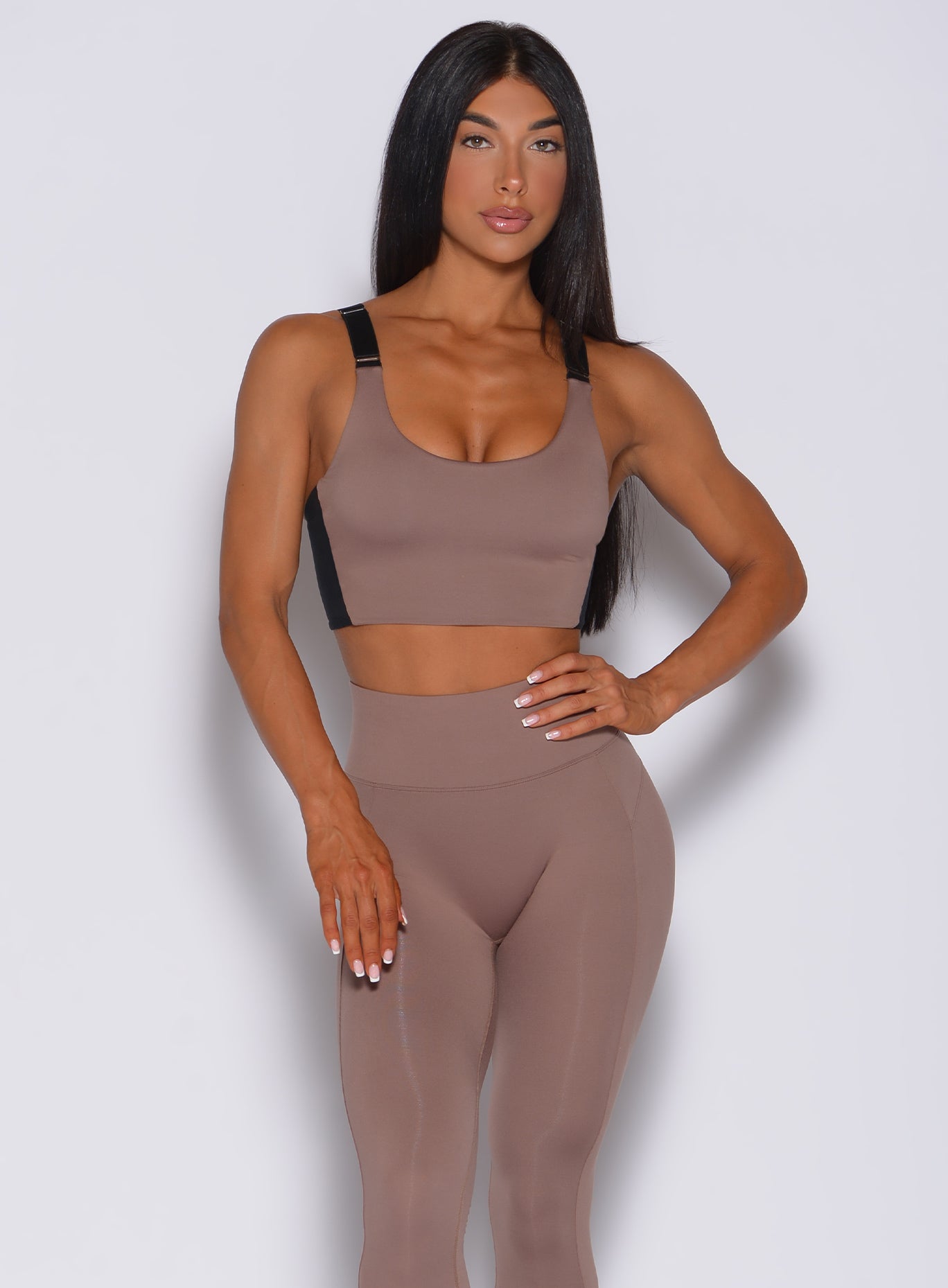 Front  profile view of a model wearing our banded sports bra in cocoa color and a matching leggings