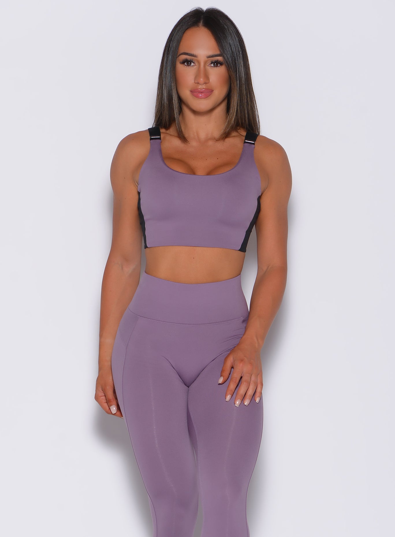 Front profile view of a model  wearing our banded sports bra in violet frost color and a matching leggings