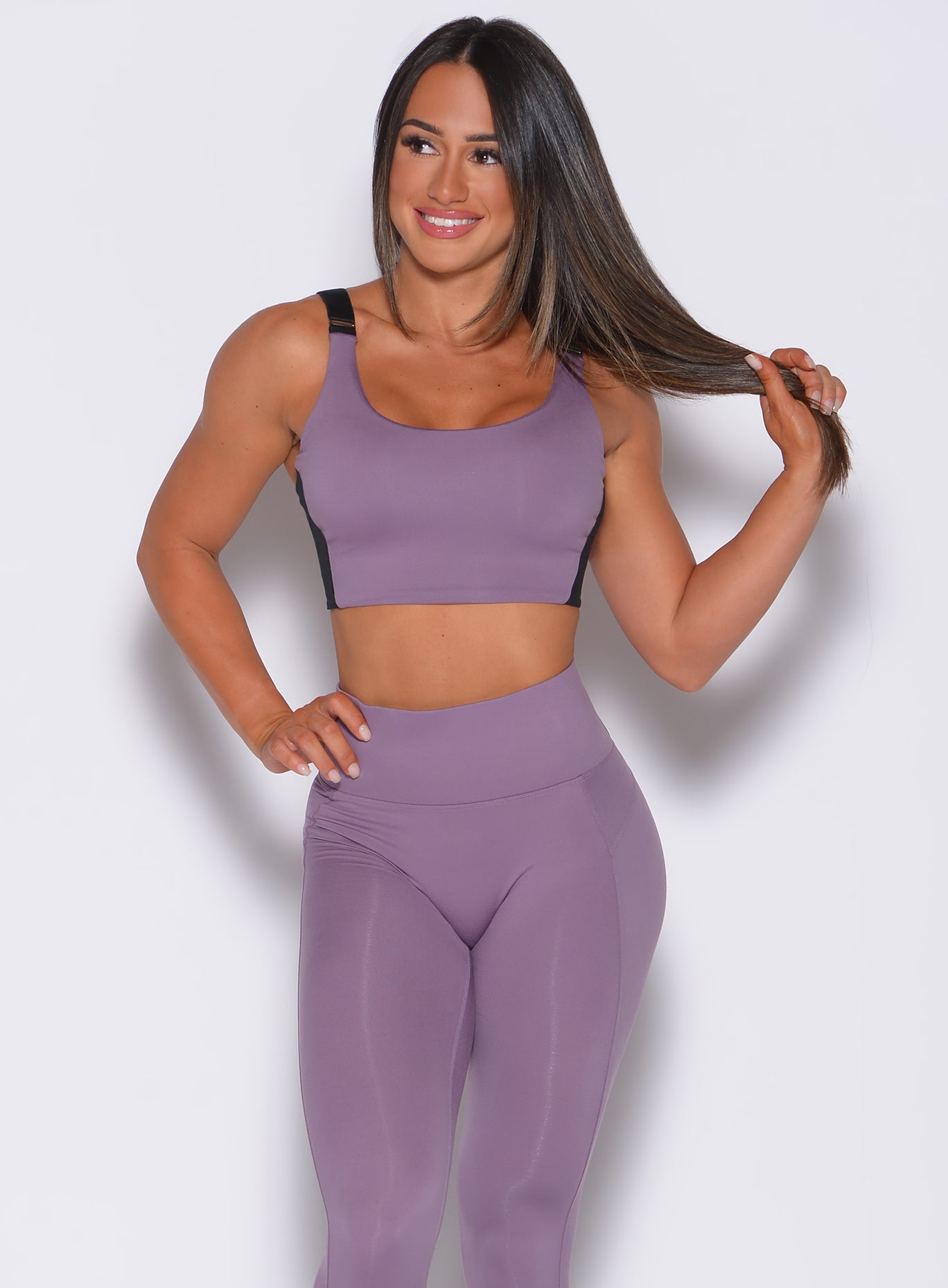 Front profile view of a model in our banded sports bra in violet frost color and a matching leggings 