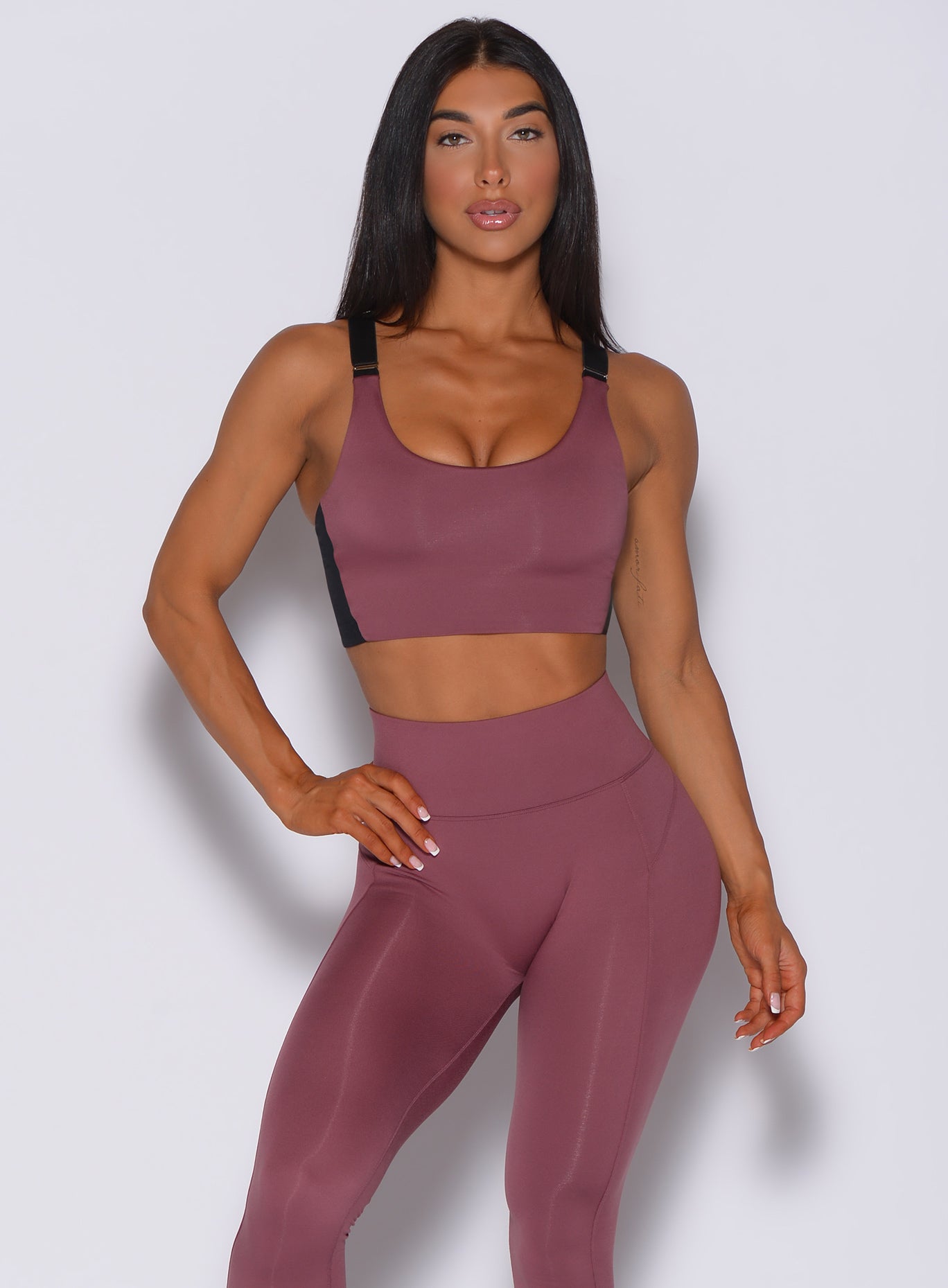 Front profile view of a model in our banded sports bra in merlot color and a matching leggings