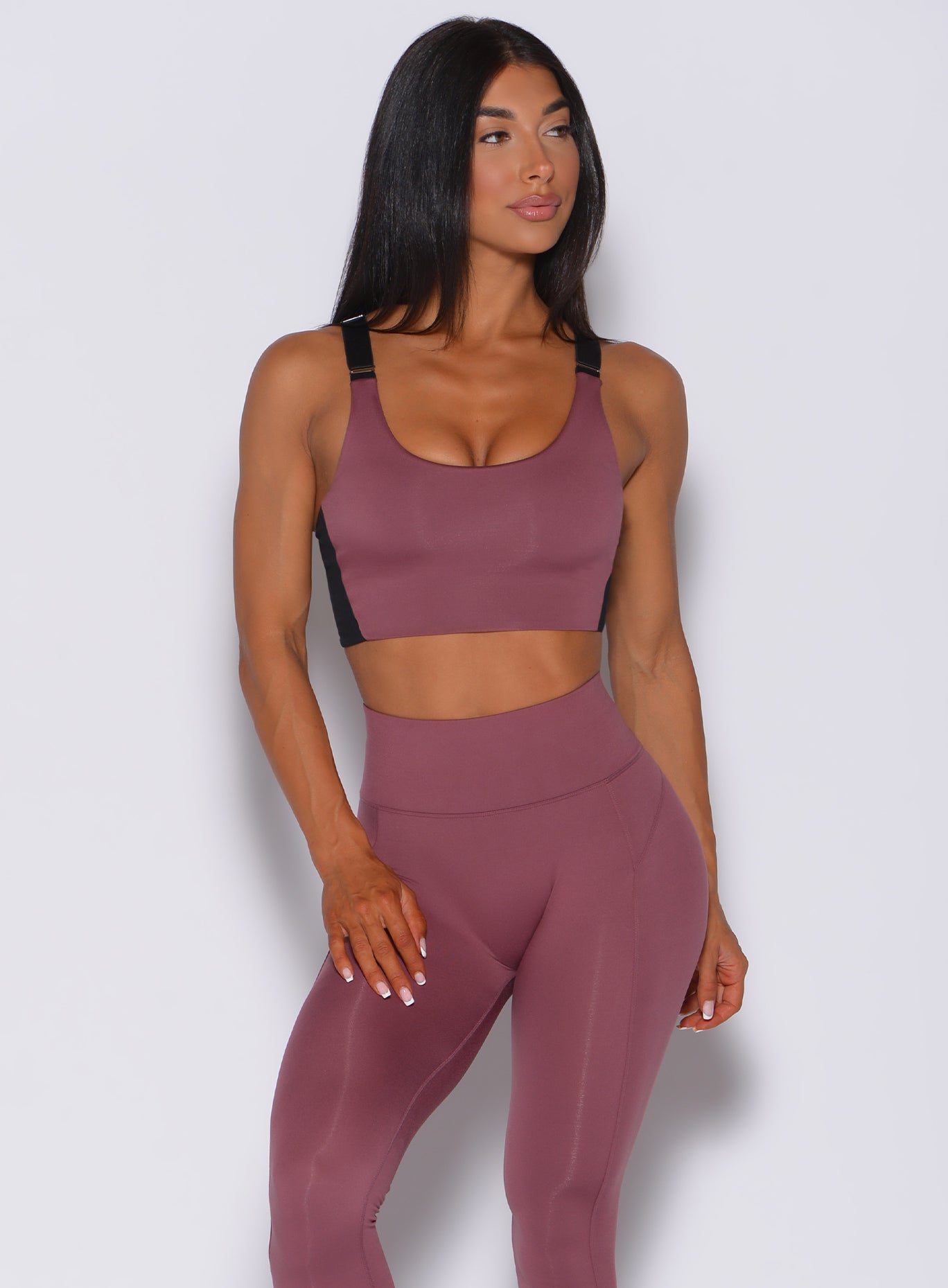 Front profile view of a model wearing our banded sports bra in merlot color and a matching leggings