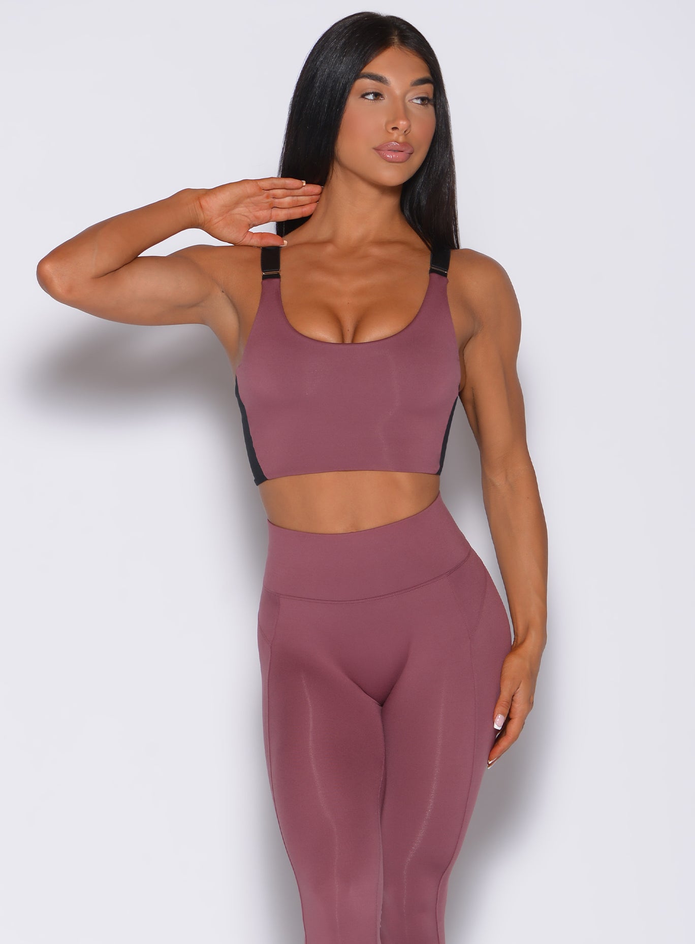 Front profile view of a model facing to her left wearing our banded sports bra in merlot color and a matching leggings