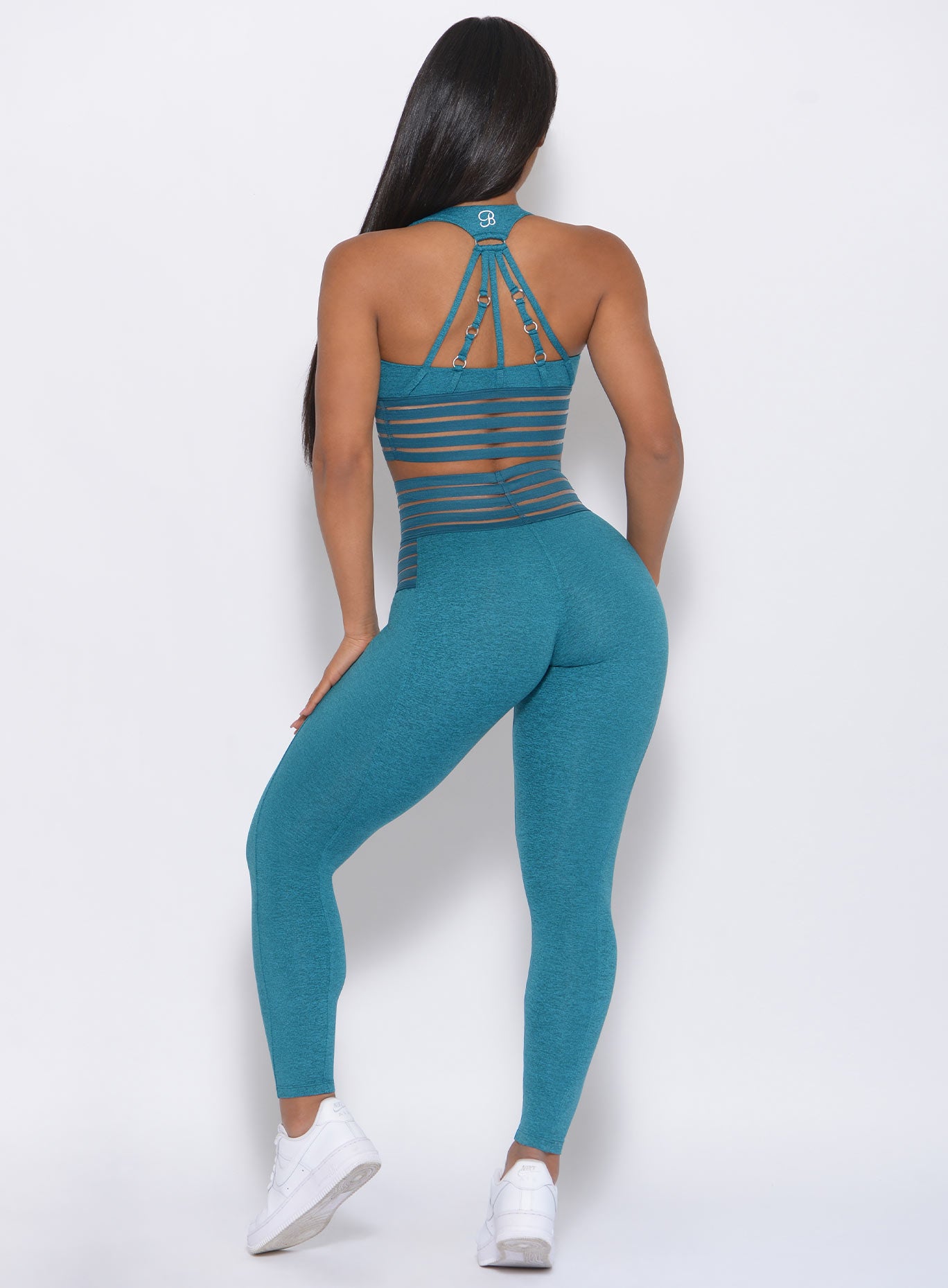 Back profile of the model  in our statement leggings in seafoam color and a matching bra