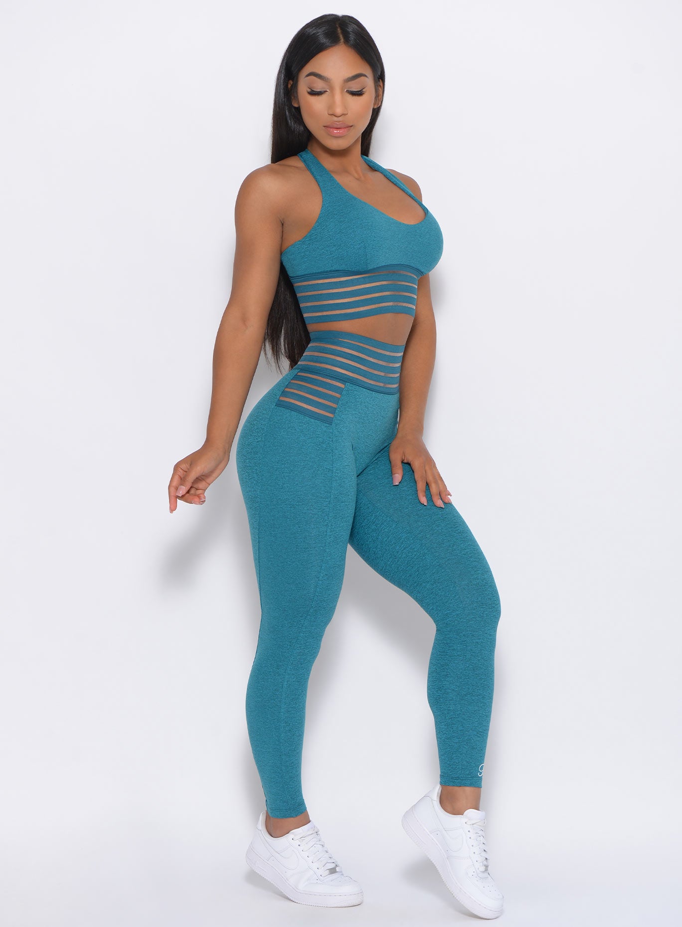 Right side view of the model angled right in our statement leggings in seafoam color and a matching bra