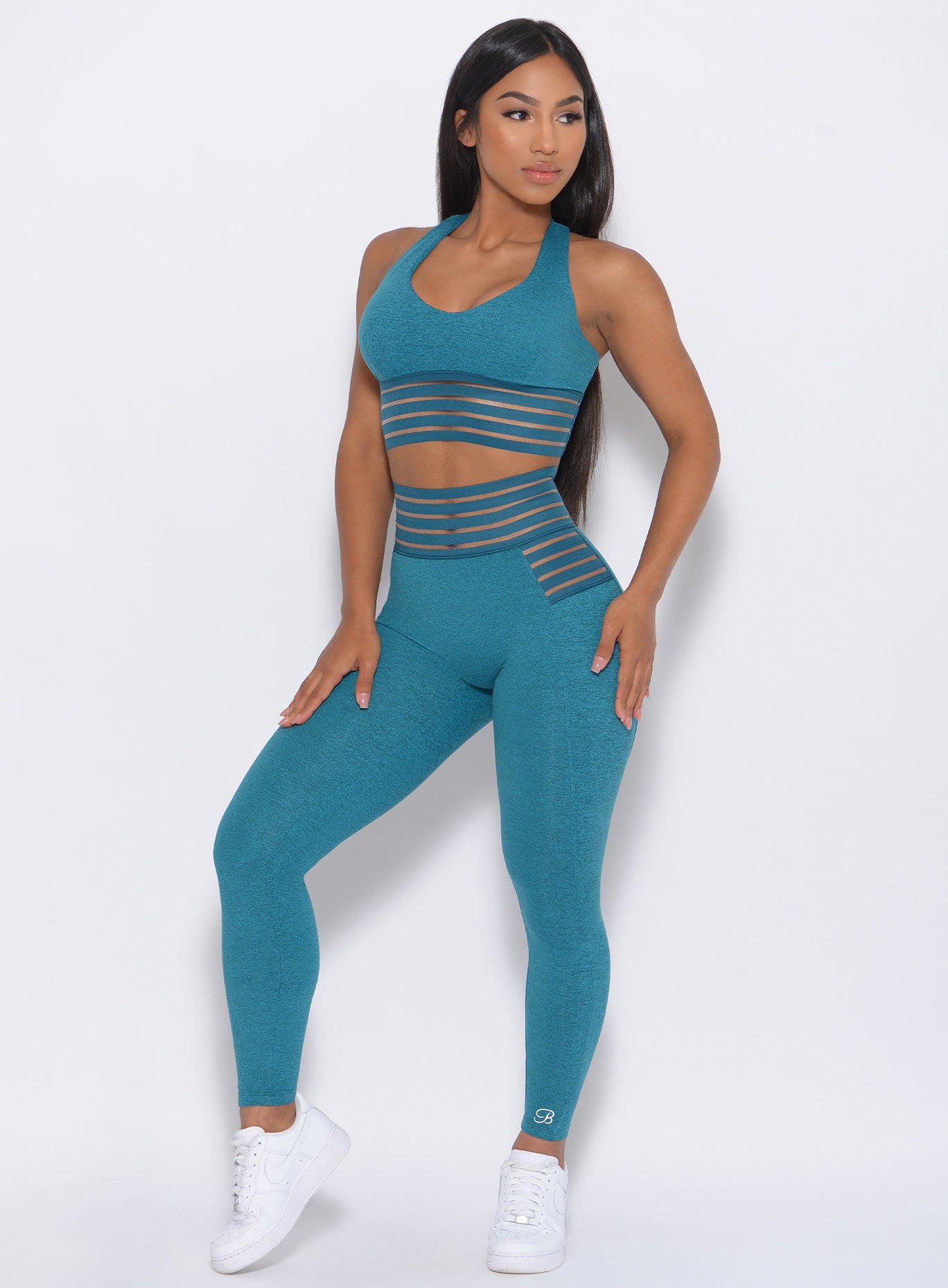 Front view of the model with her hands on thighs wearing our statement leggings in seafoam color and a matching bra