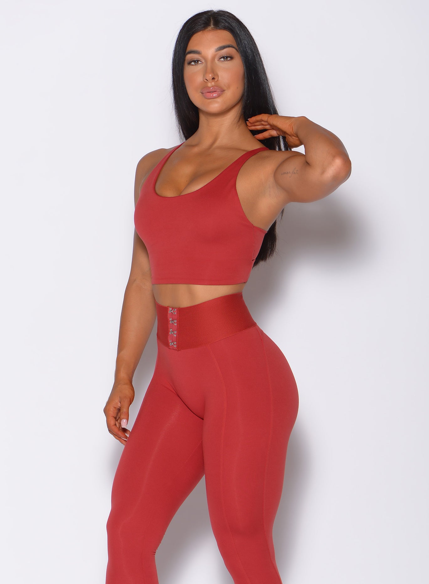 Model facing for ward wearing our impact sports bra in sunset red and a matching leggings 
