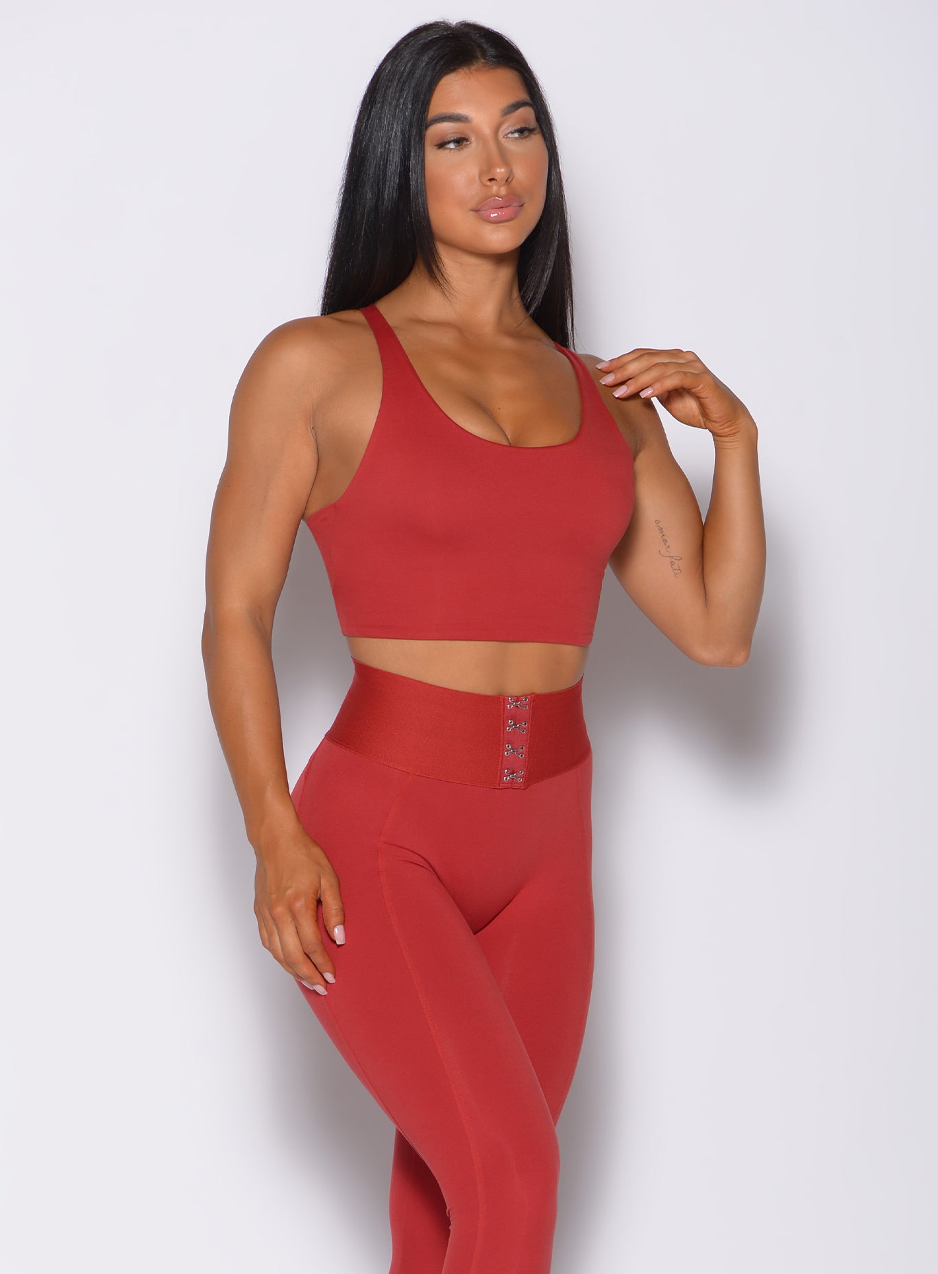 Front profile view of a model in our impact sports bra in sunset red and a matching high waist leggings