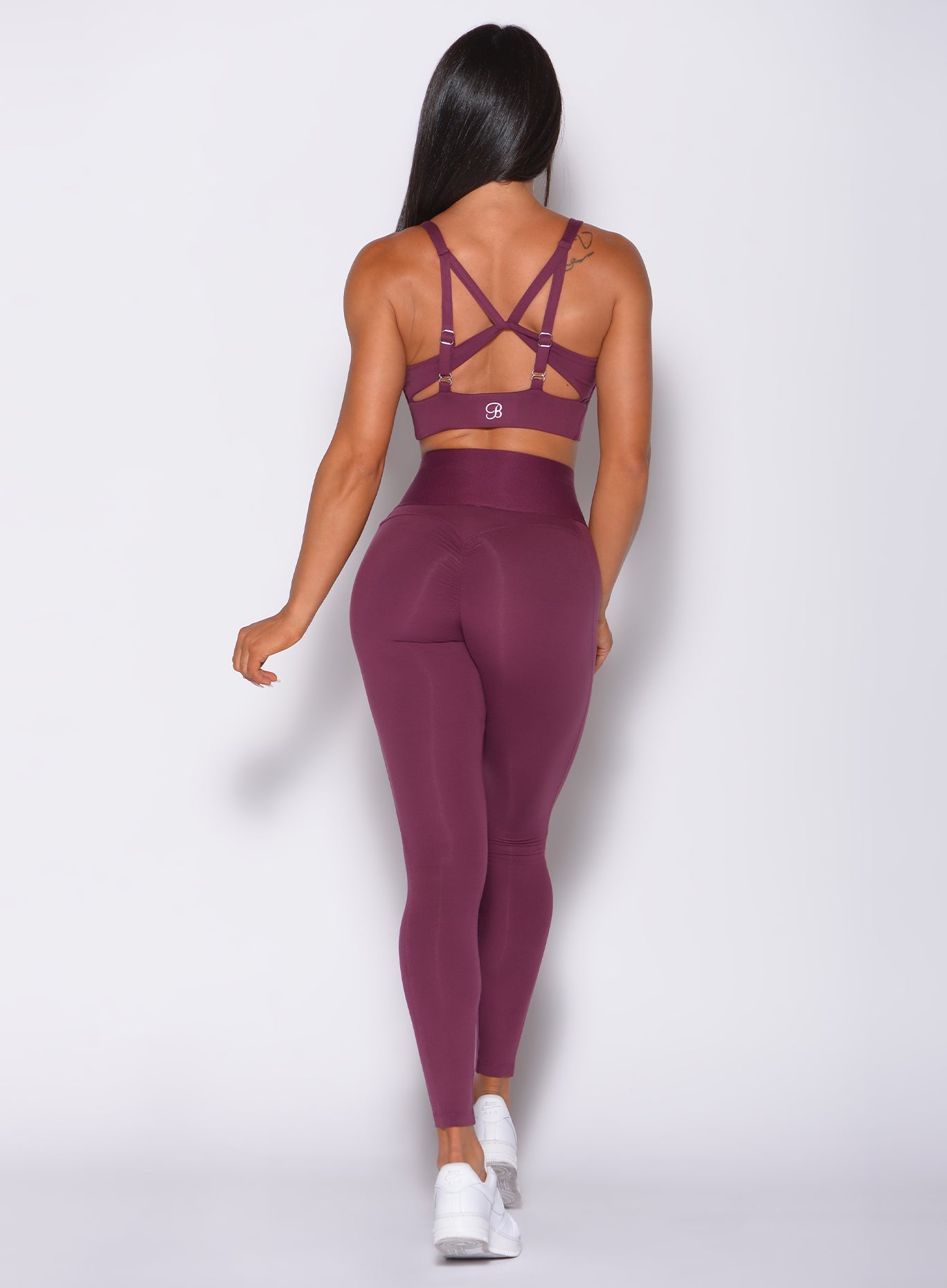 Back  profile view of a model in our waist cincher leggings in majestic purple color and a matching bra